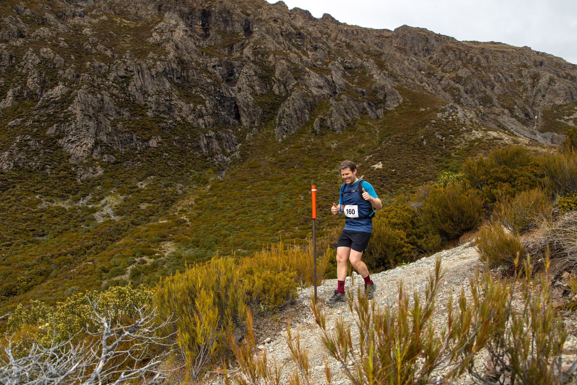 A man is running on a trail in the mountains.