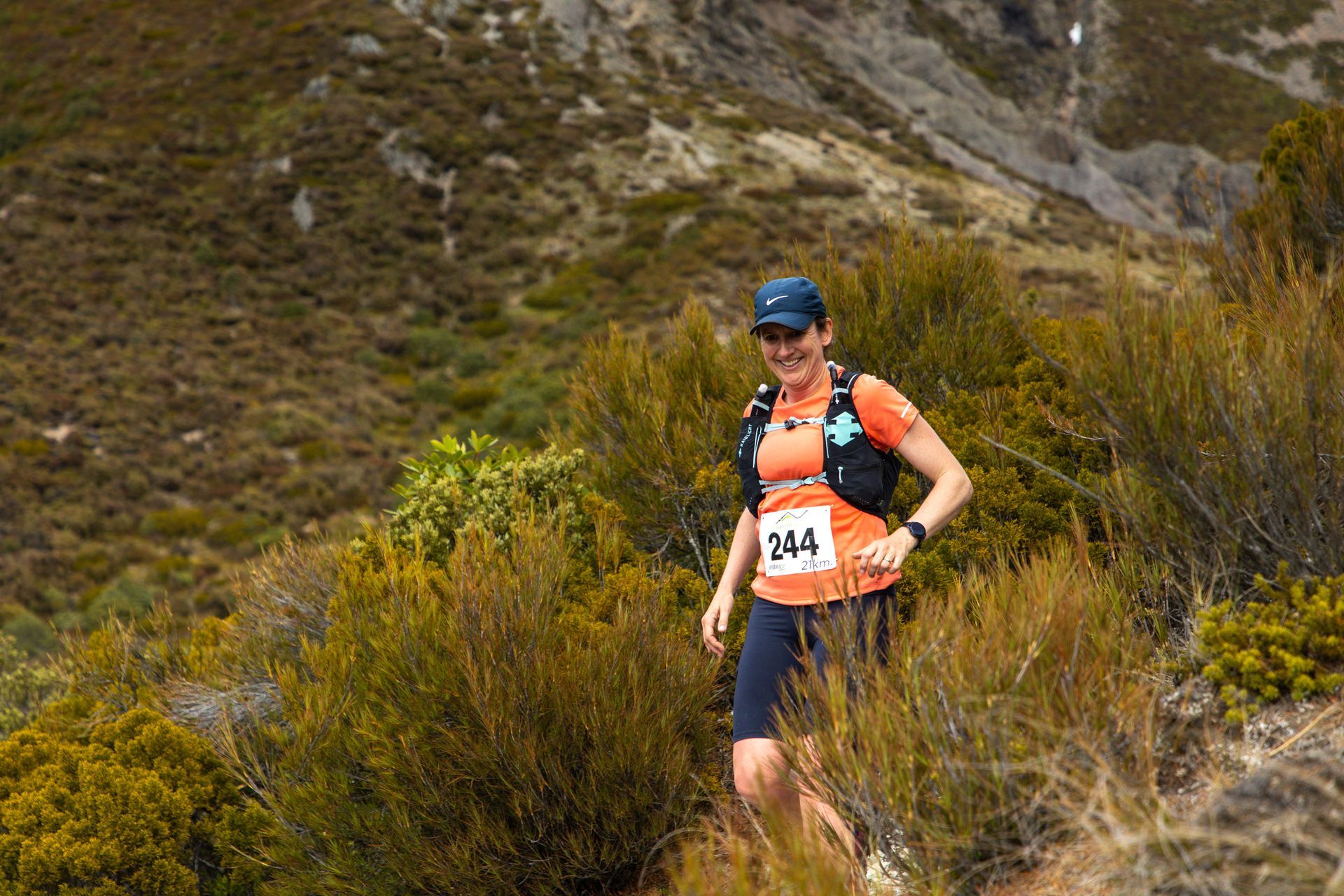 A woman is running on a trail in the mountains.