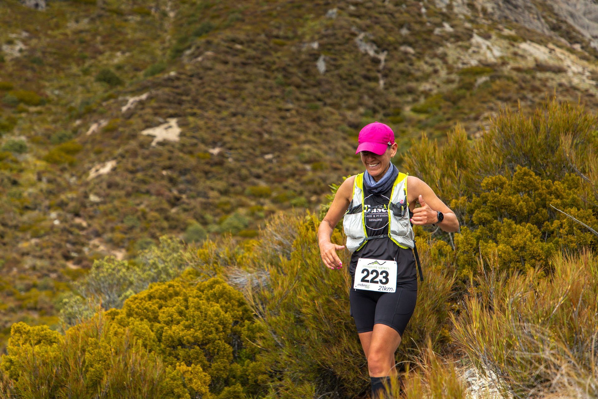 A woman is running on a trail in the mountains.