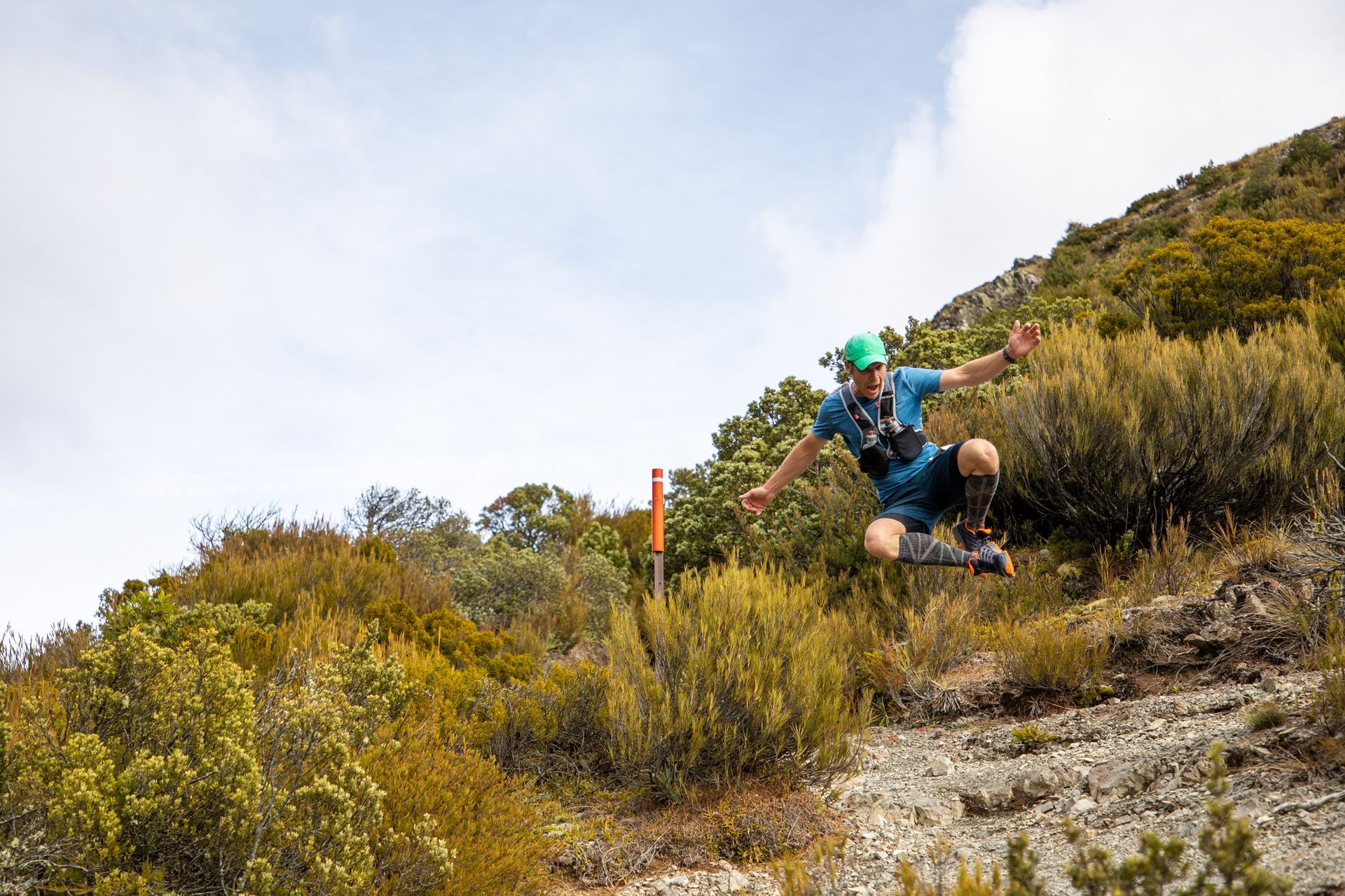 A man is running down a hill in the woods.