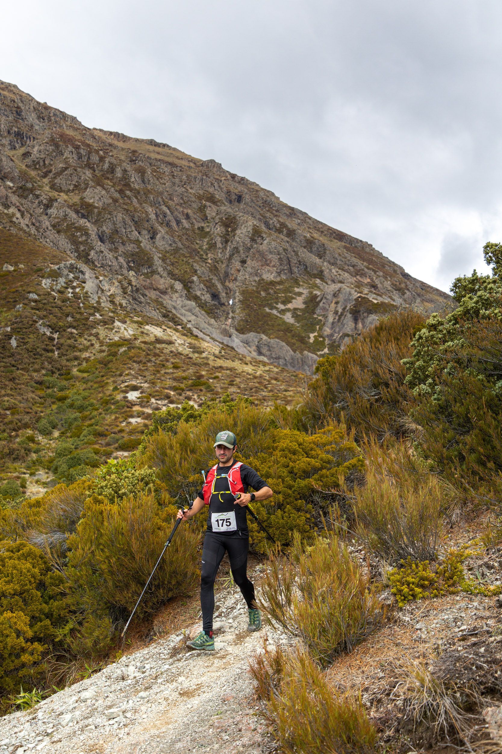 A man is walking on a dirt path in the mountains.