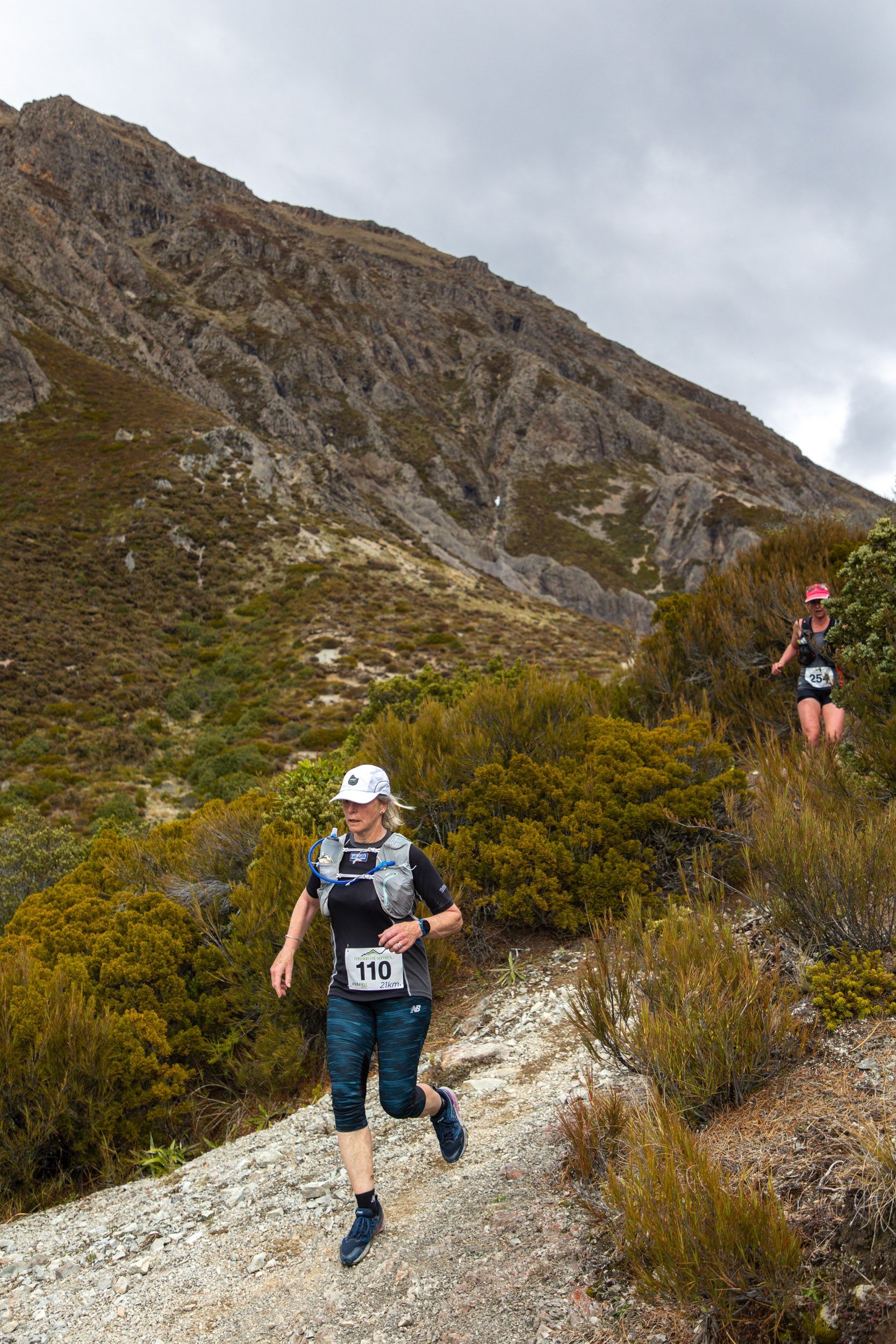 A man and a woman are running up a hill.