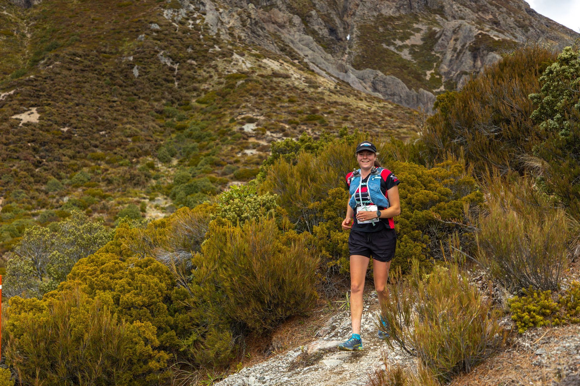 A woman is running on a trail in the mountains.