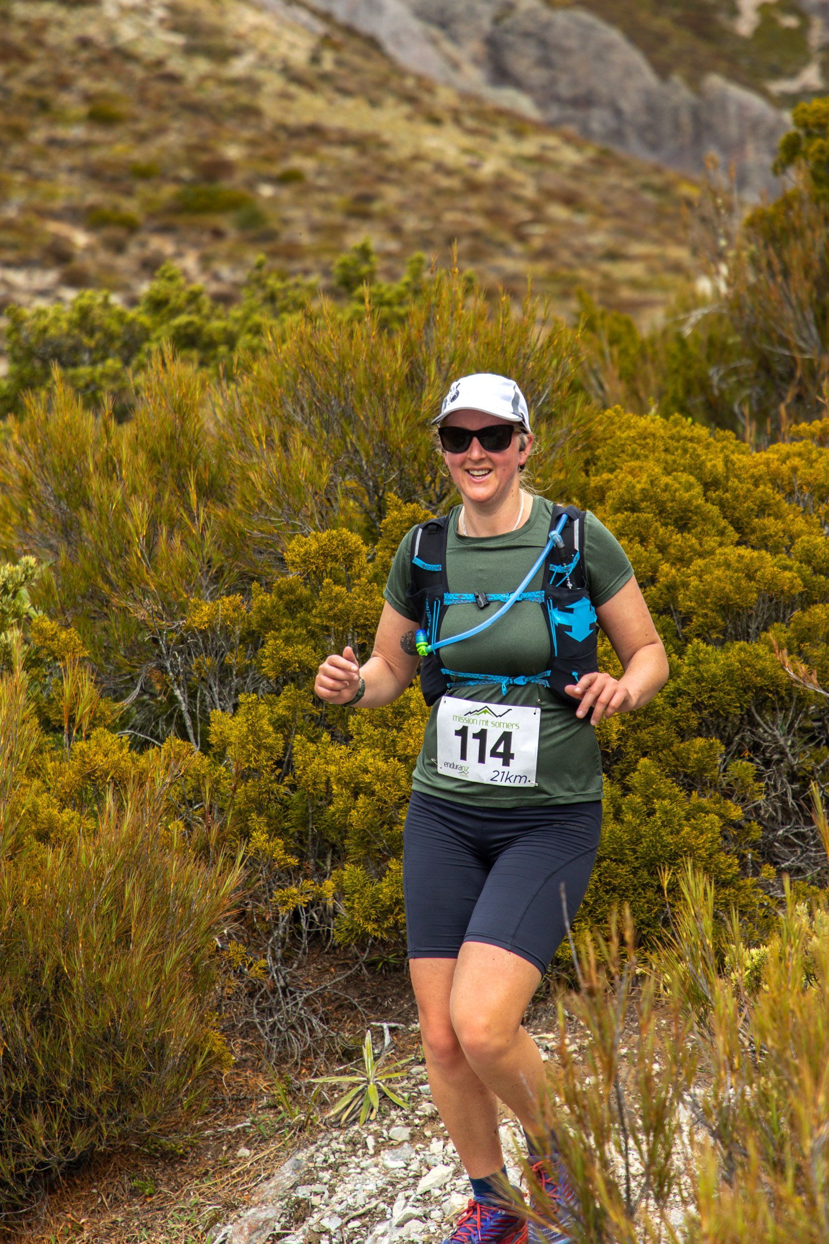 A woman is running on a trail in the mountains.