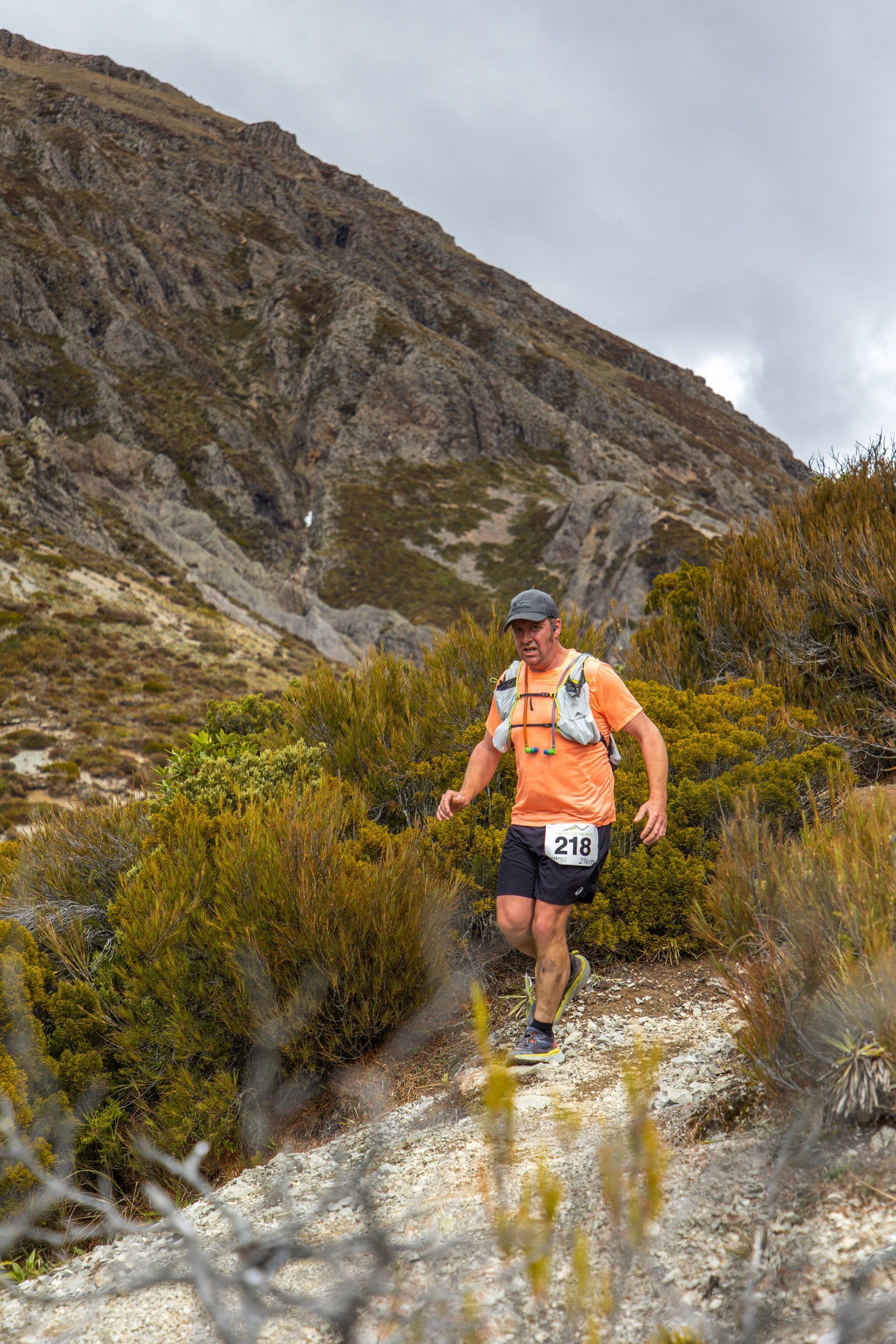 A man is running on a trail in the mountains.