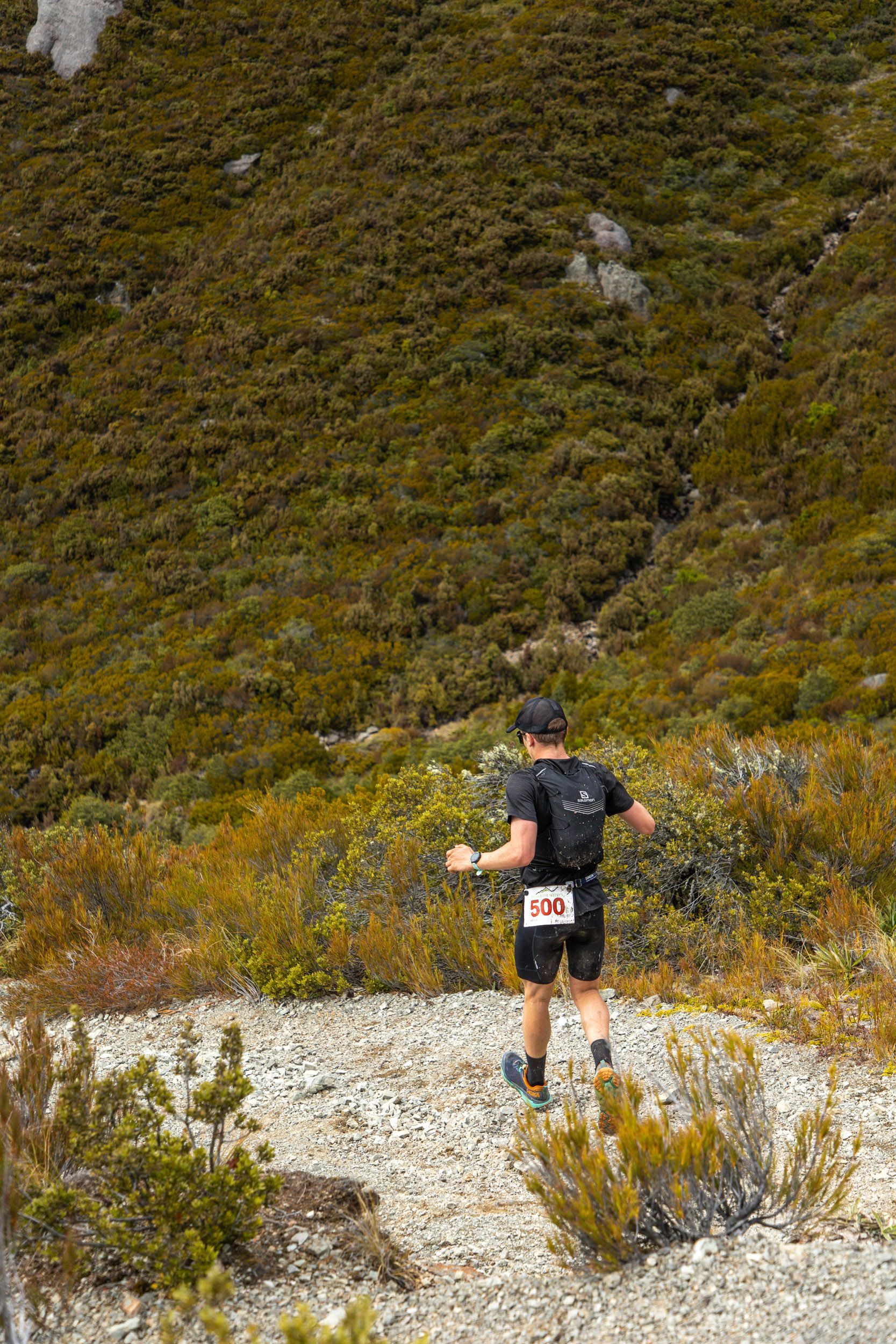 A man is running on a trail in the mountains.
