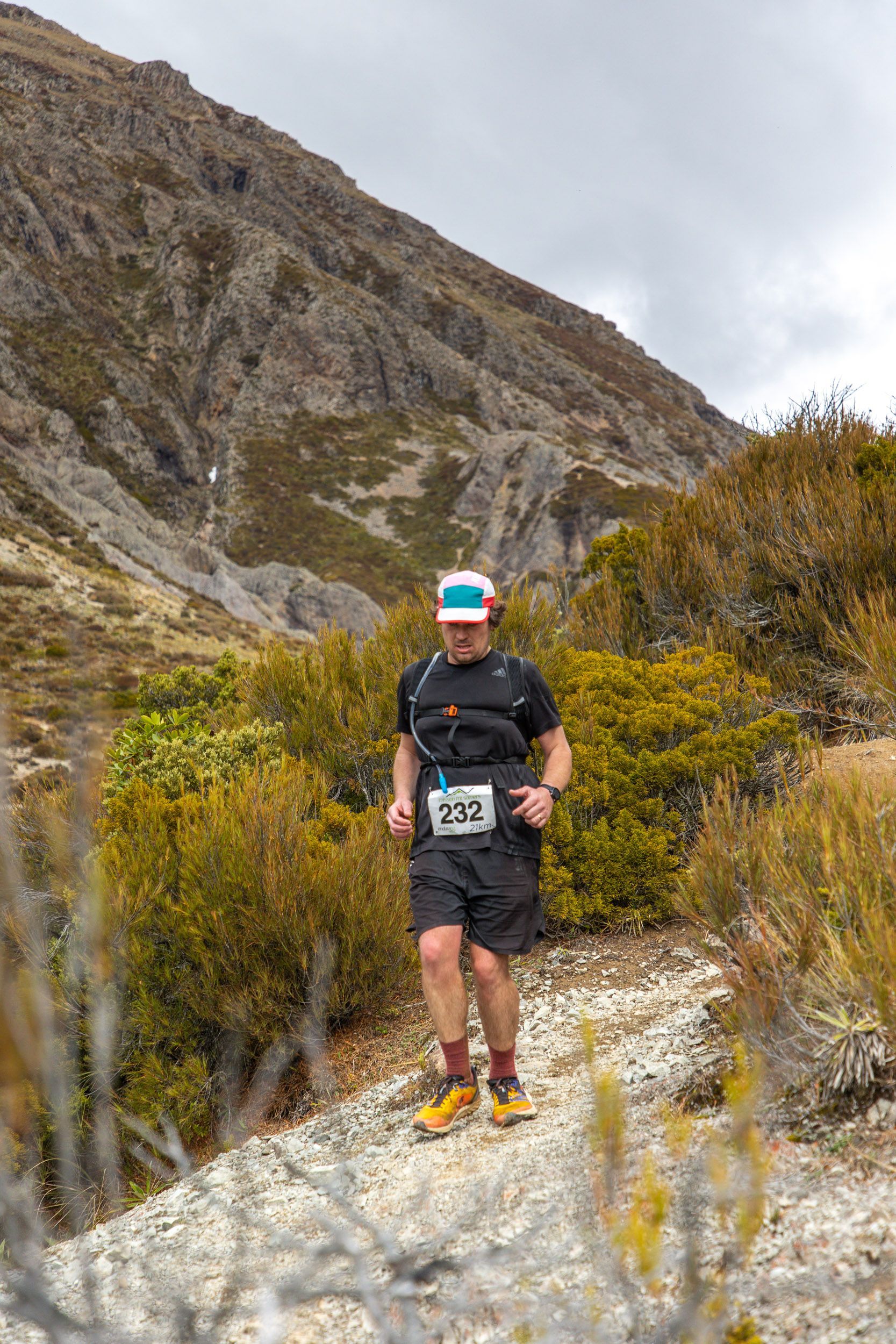 A man is running on a trail in the mountains.