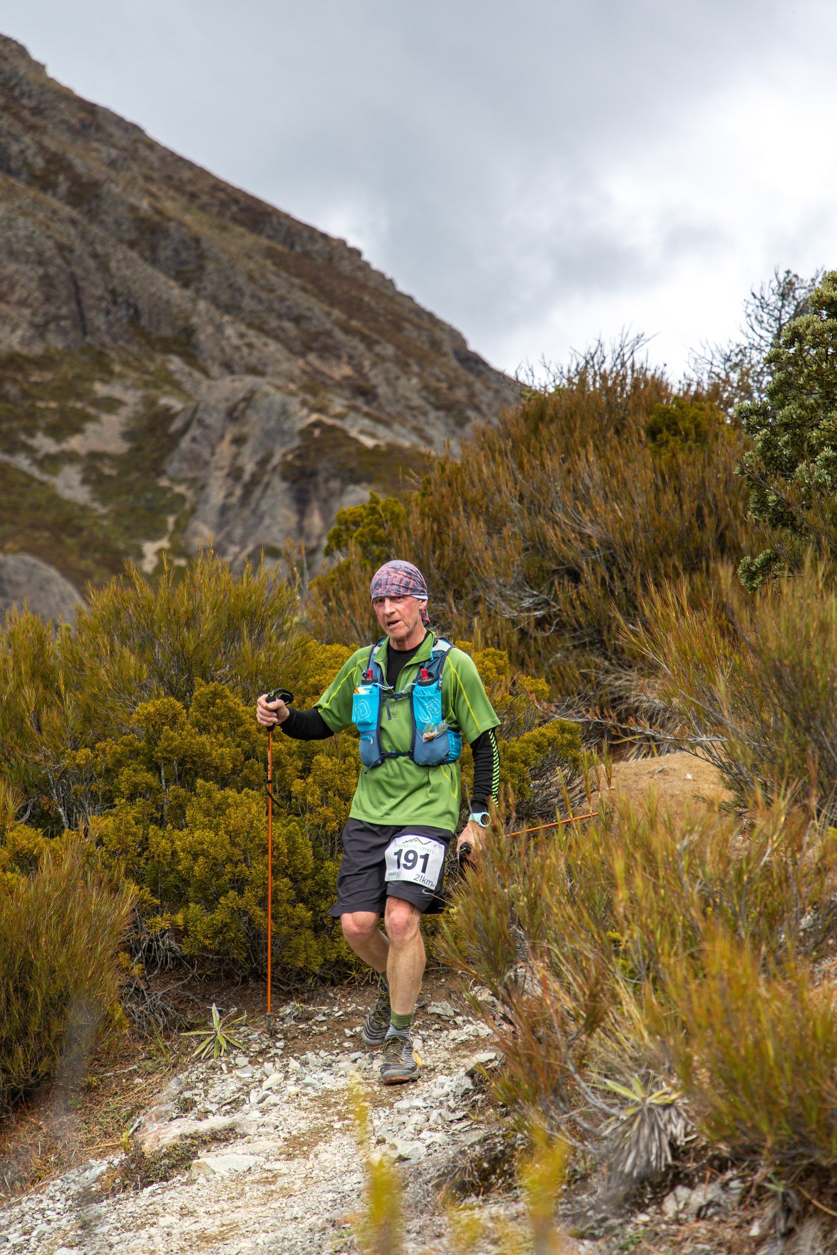 A man is running on a trail in the mountains.