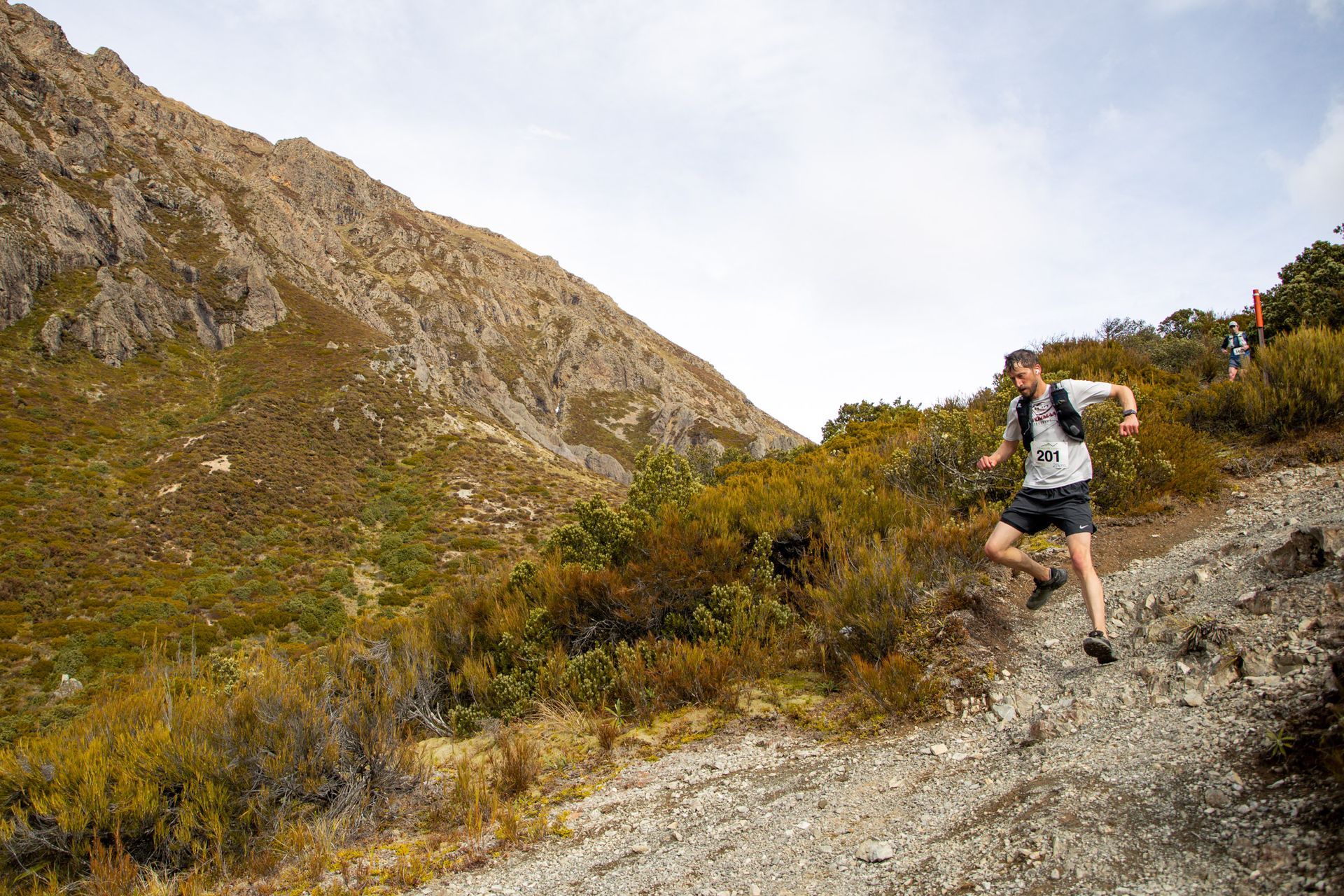 A man is running down a dirt path in the mountains.