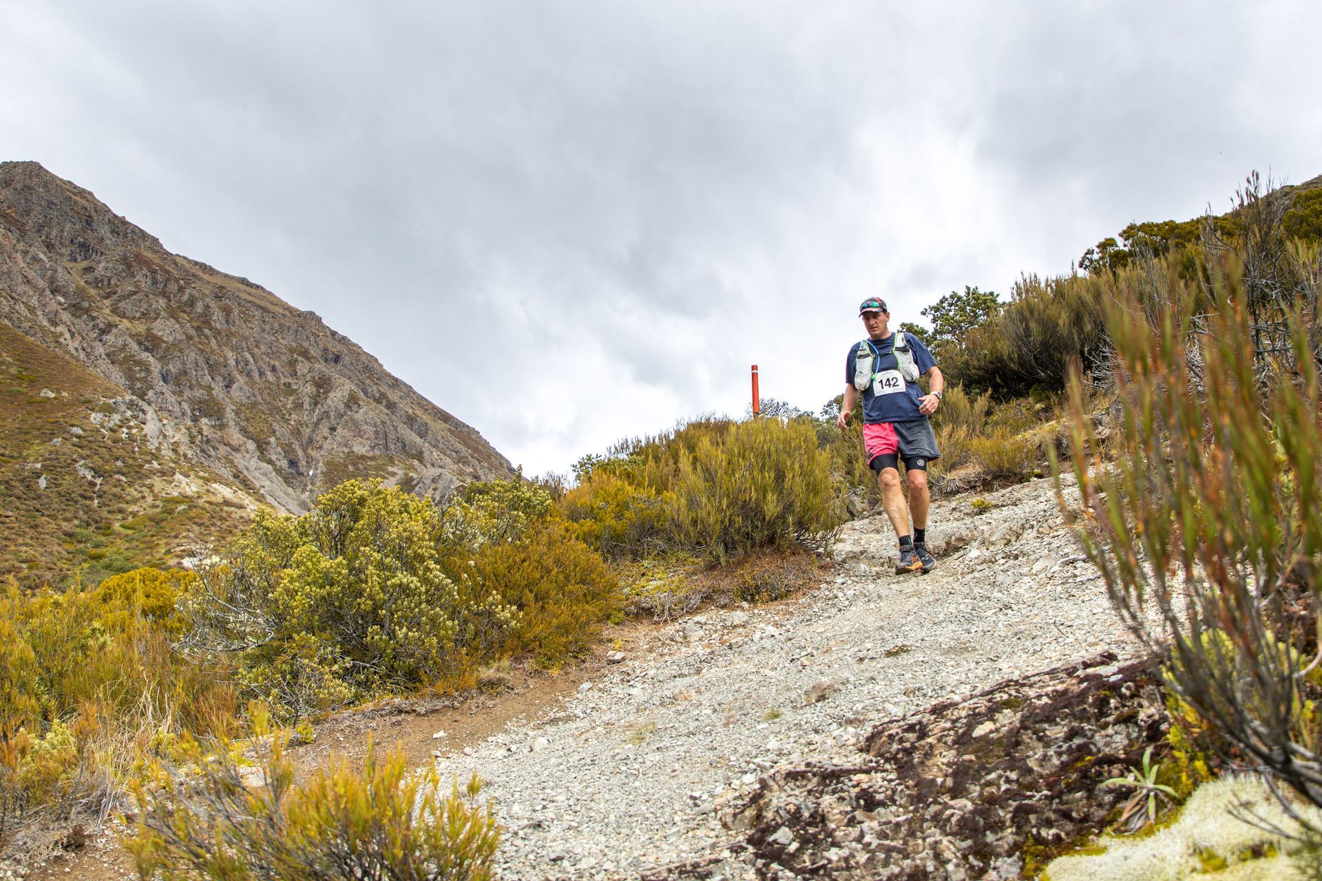 A man is running down a dirt path in the mountains.