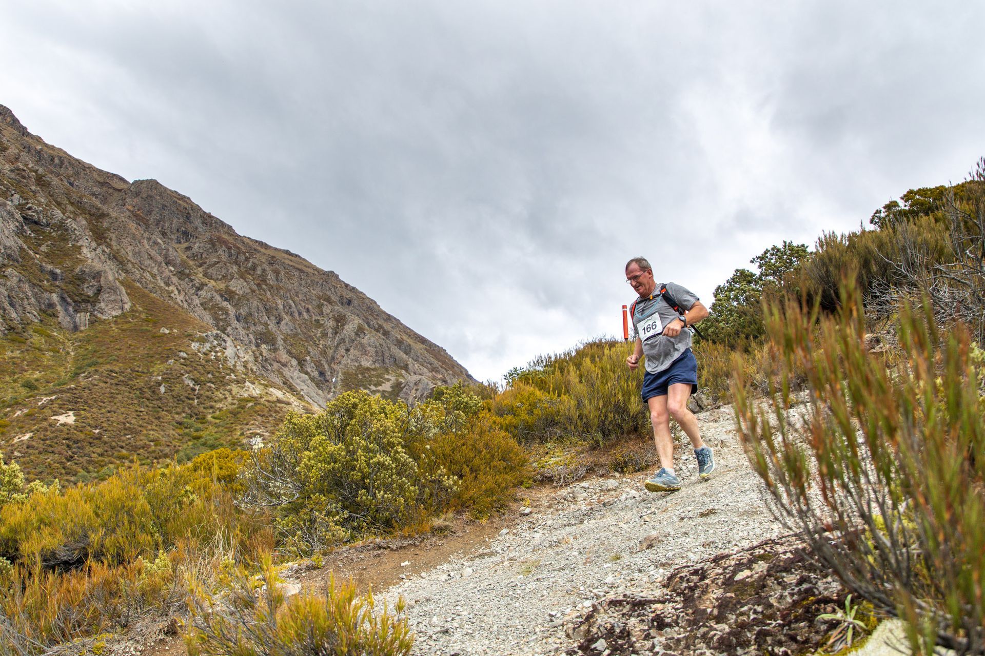 A man is running down a dirt path in the mountains.