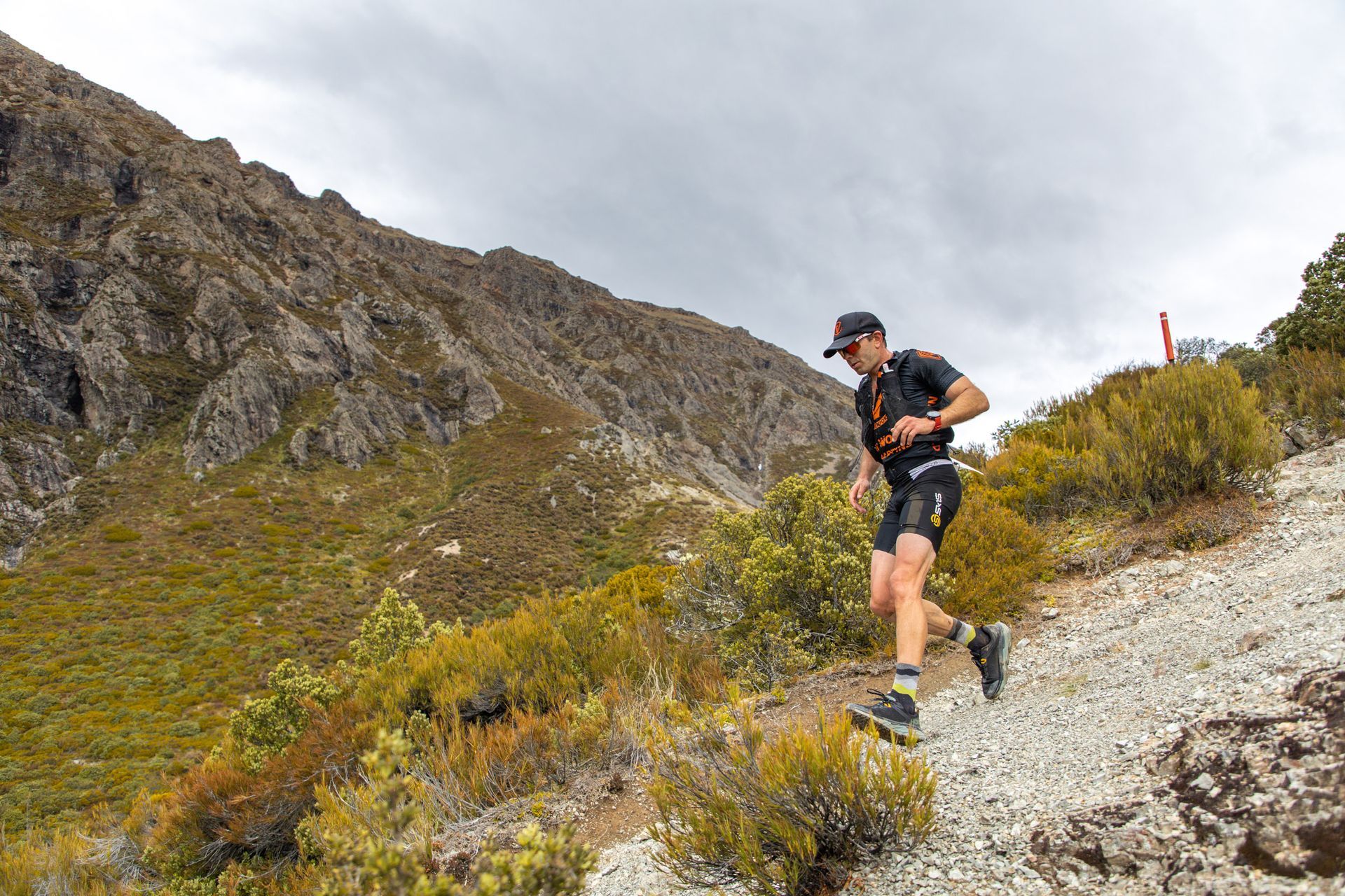 A man is running on a trail in the mountains.