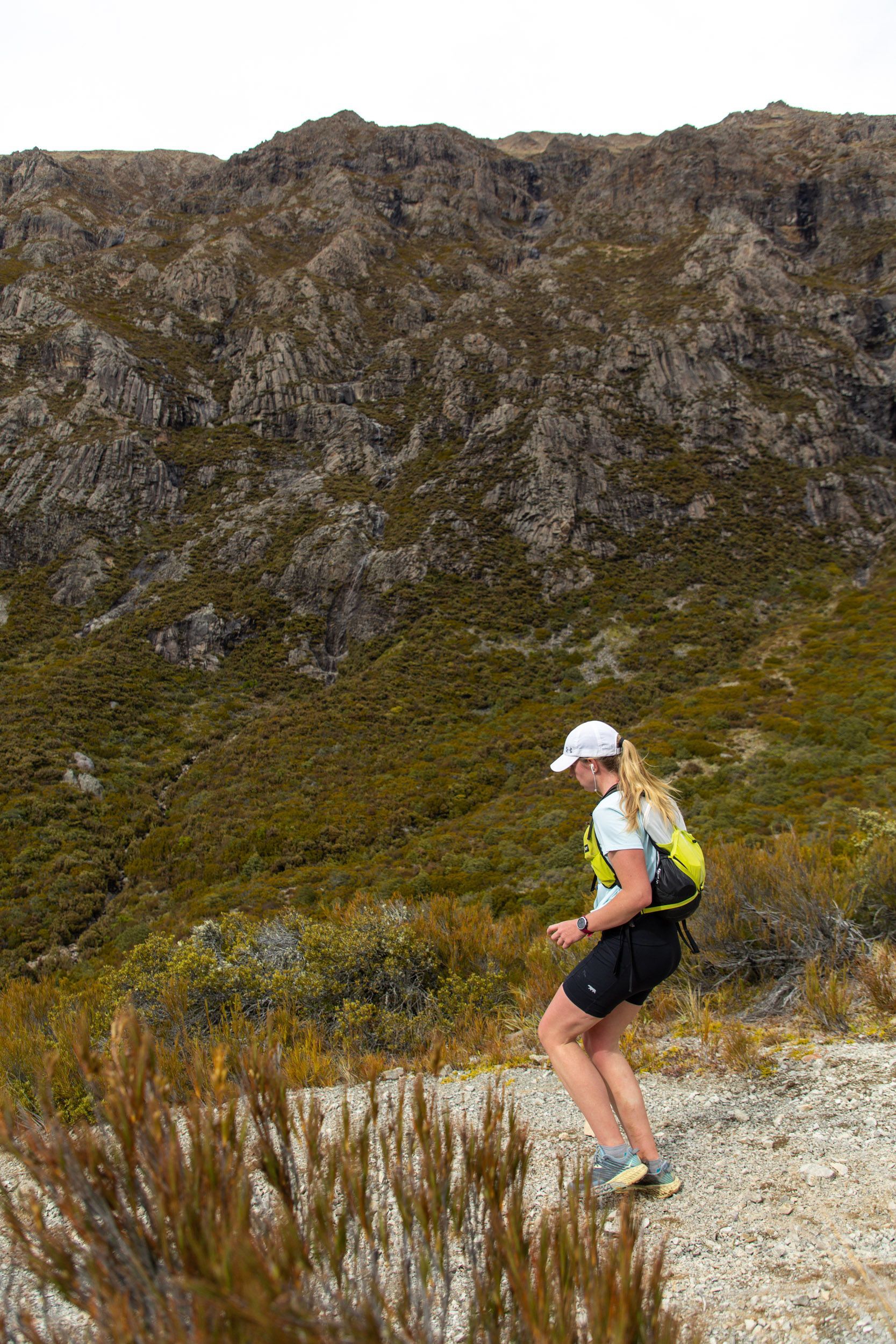 A woman is running on a trail in the mountains.