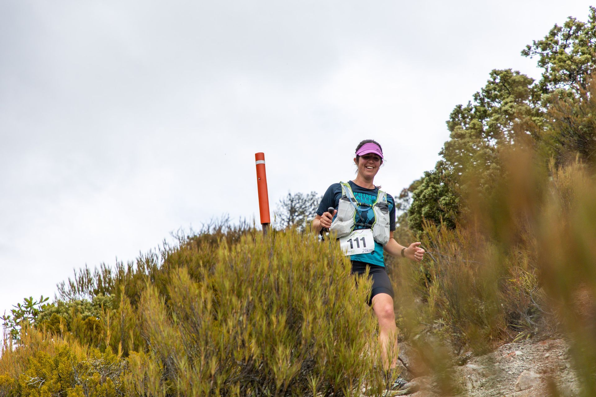 A woman is running on a trail in the woods.