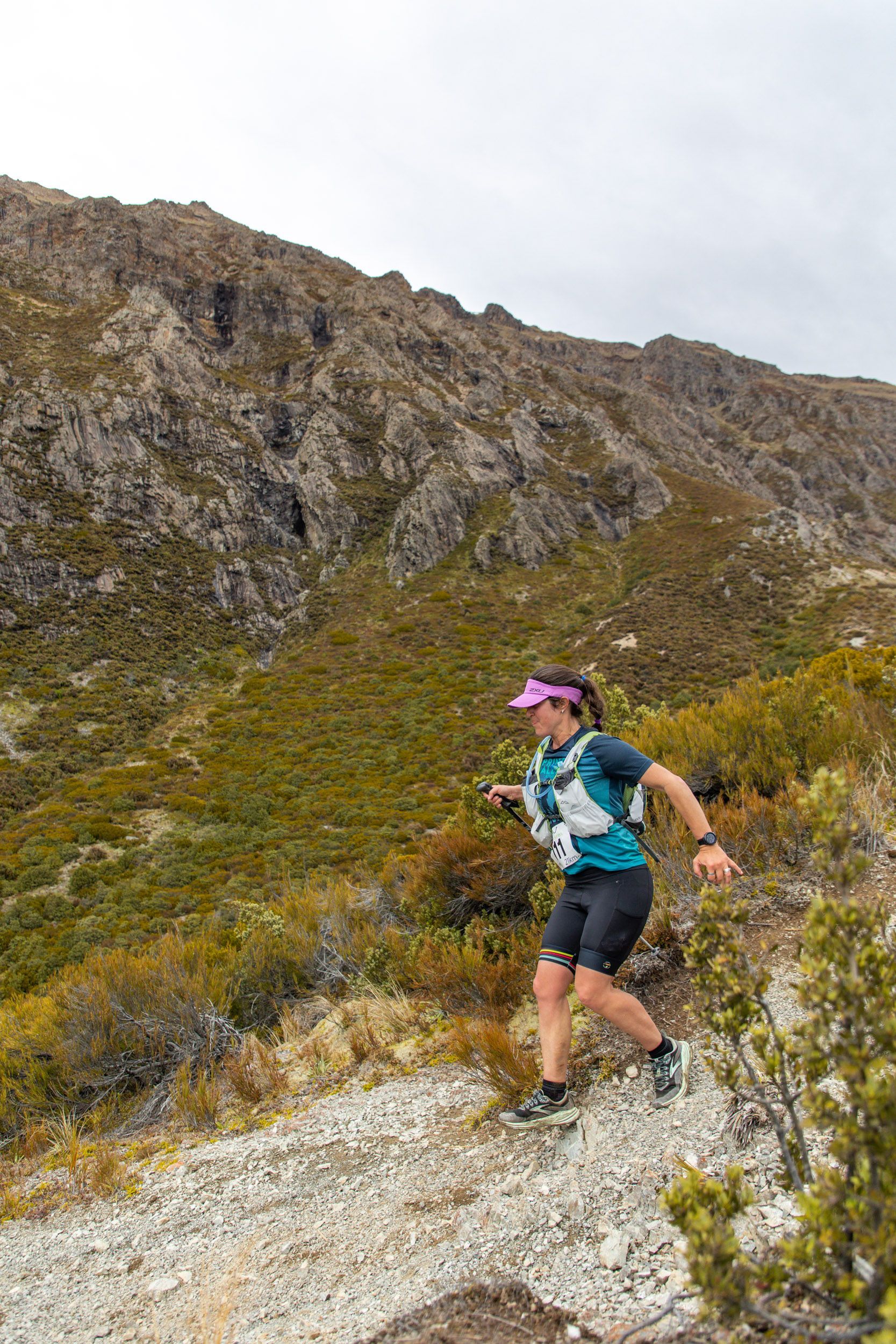 A woman is running on a trail in the mountains.