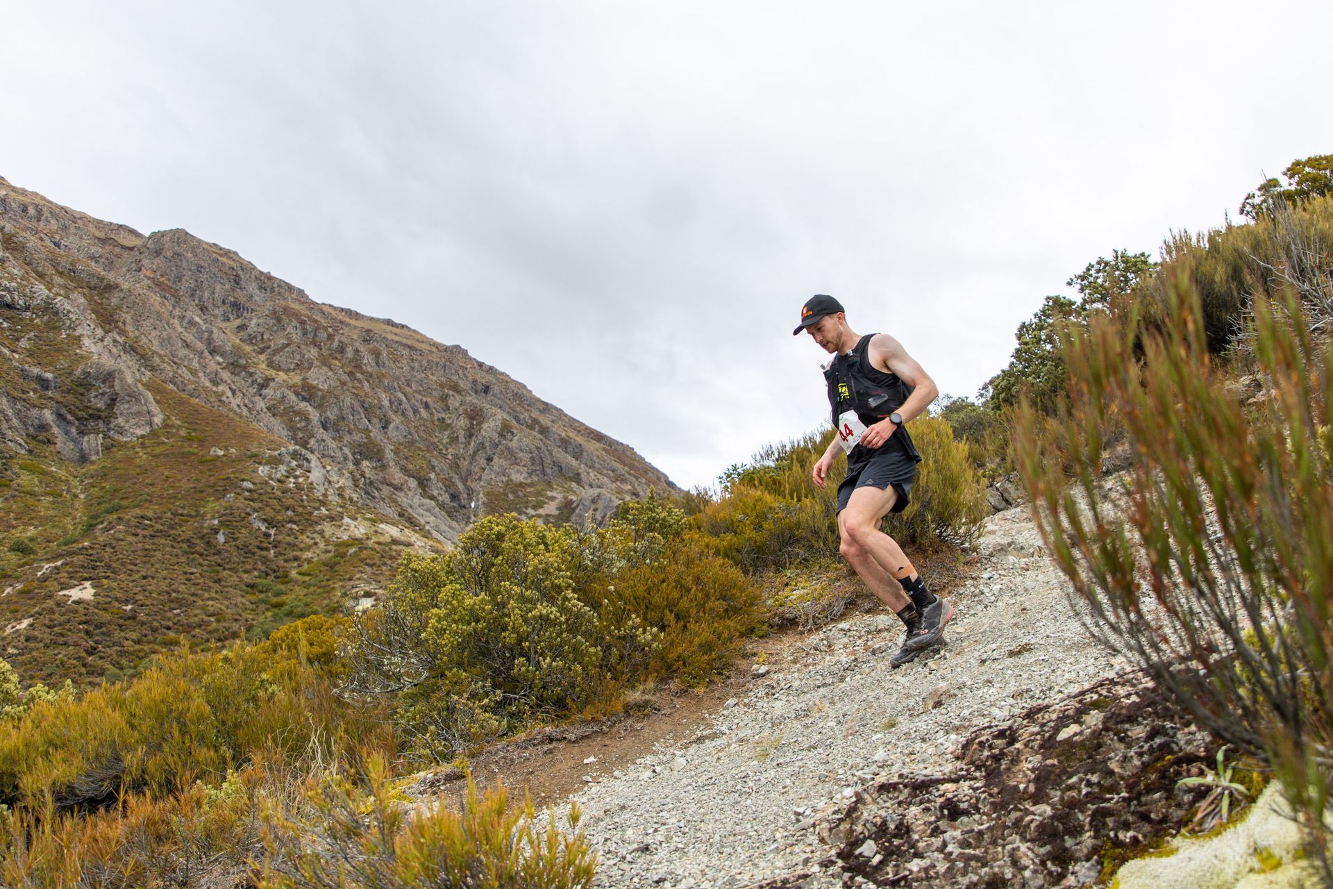 A man is running on a trail in the mountains.