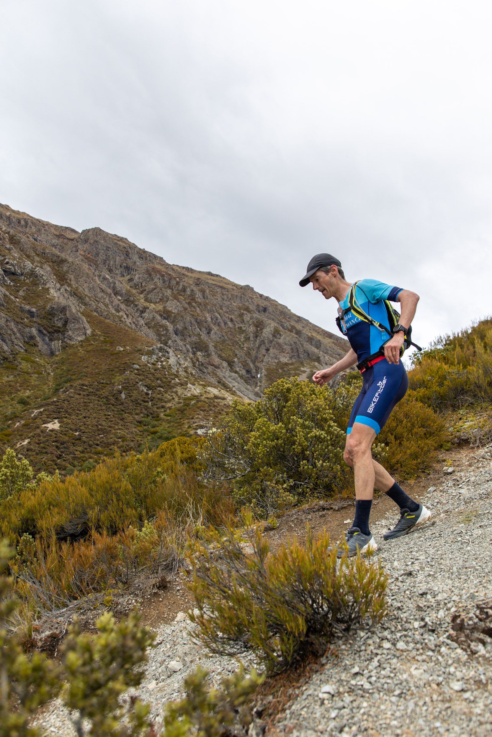 A man is running down a dirt path in the mountains.