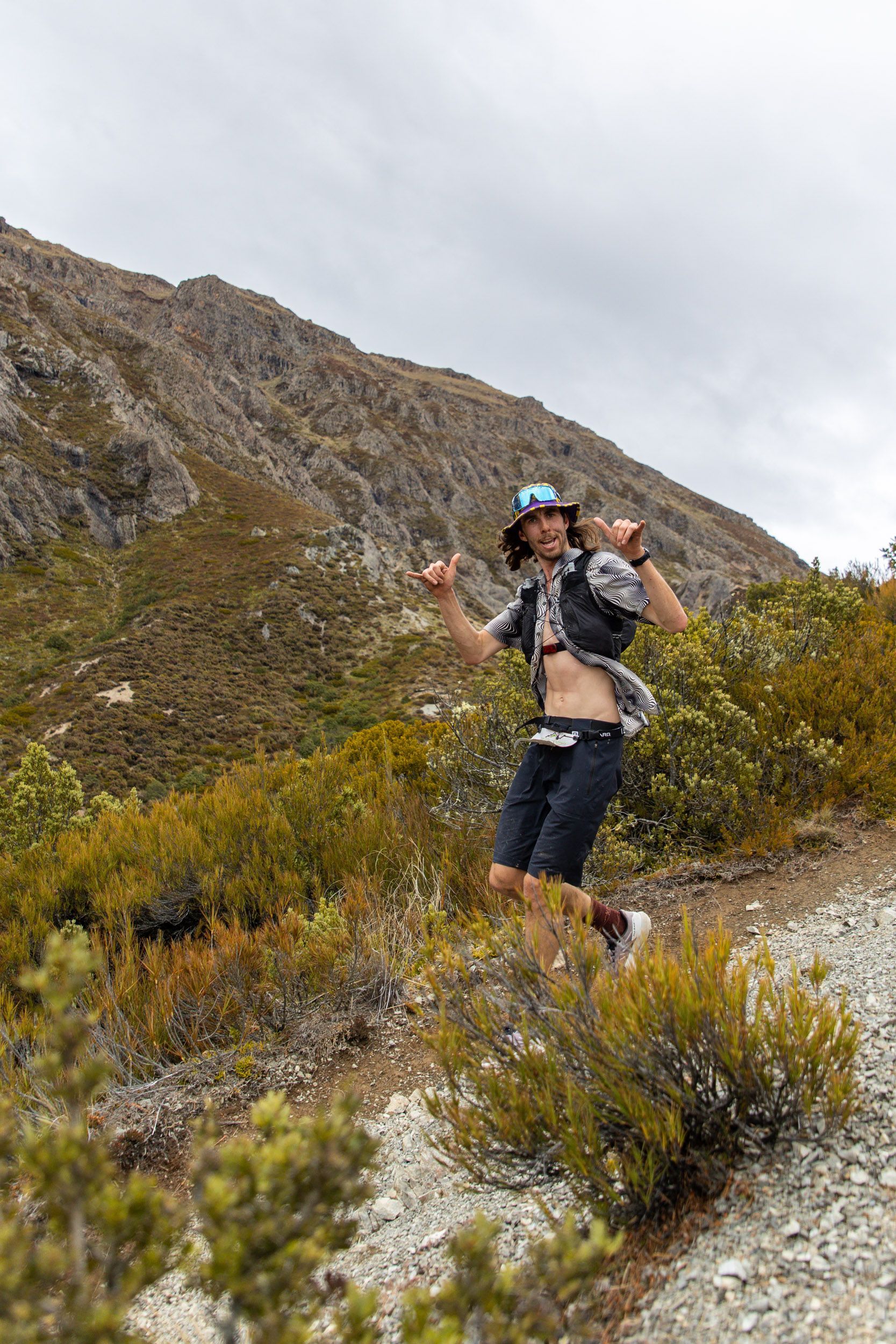 A man is running down a dirt road in the mountains.