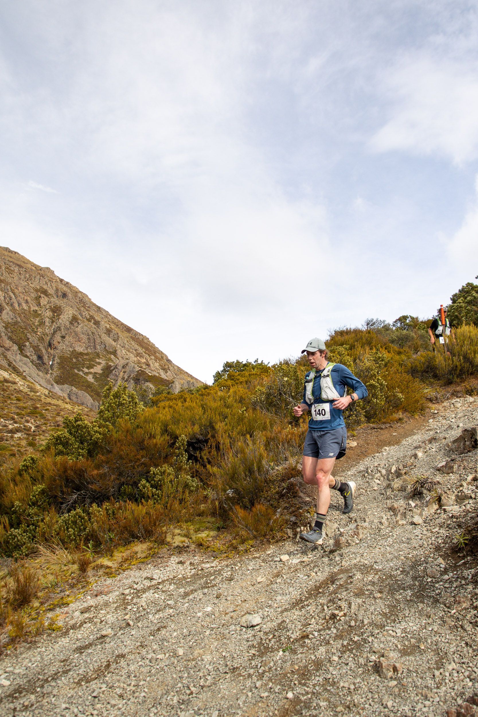 A man is running up a hill on a dirt road.