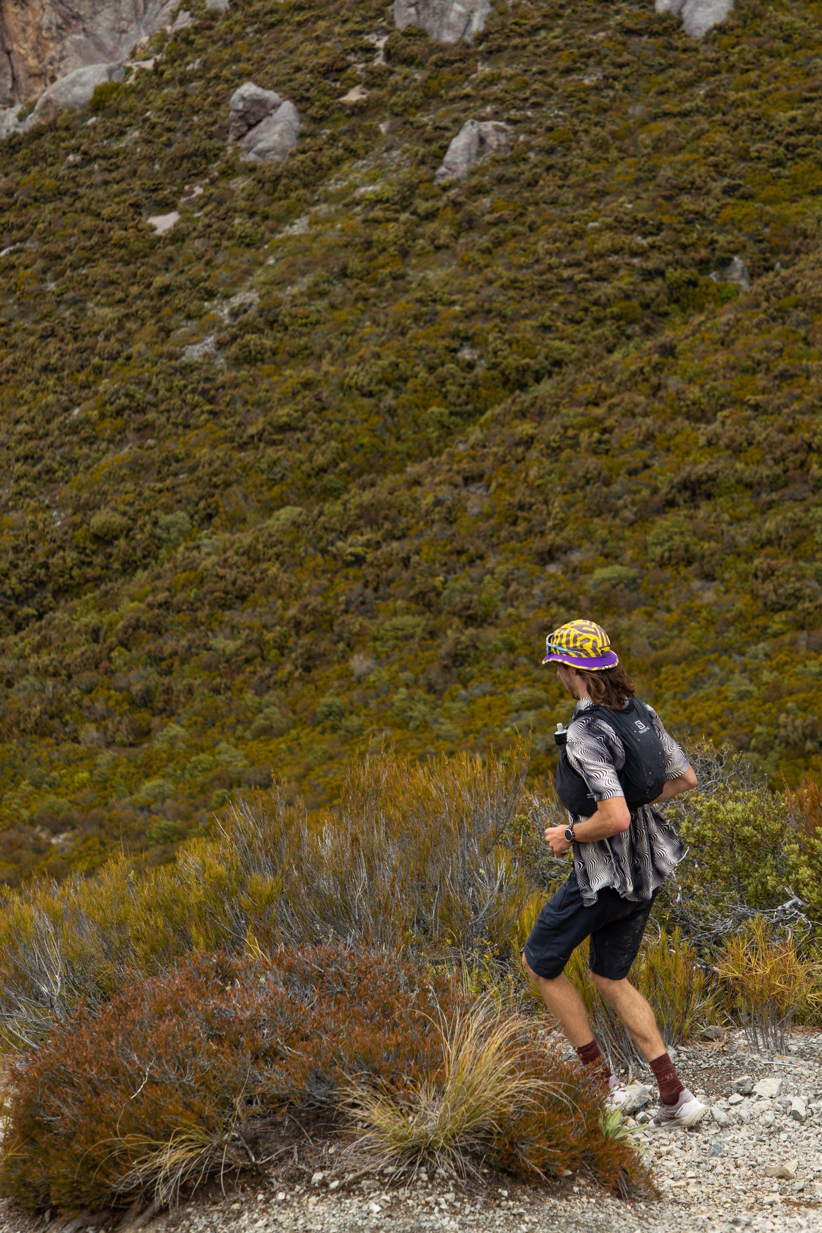 A man is walking down a dirt path in the mountains.