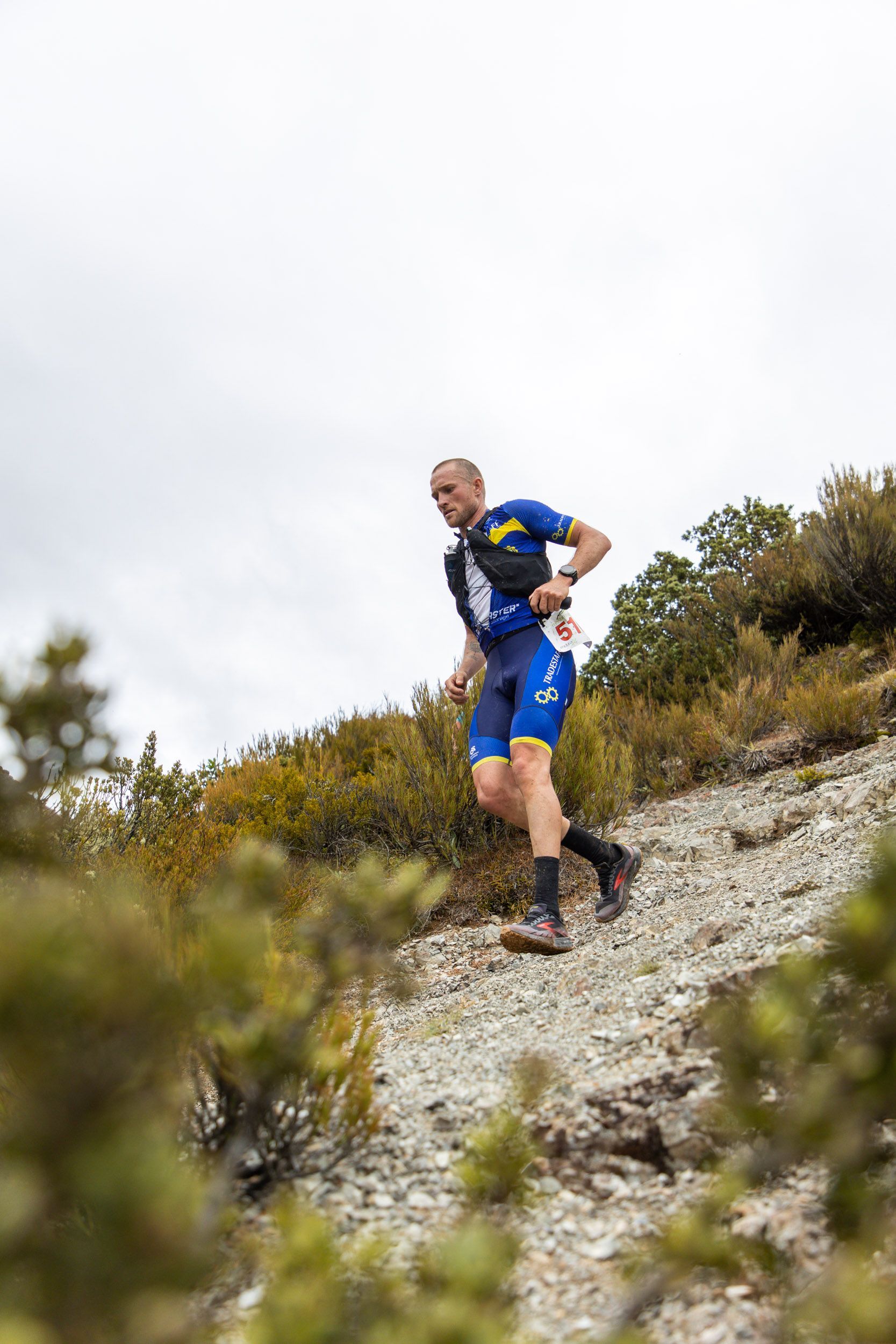 A man is running up a hill on a trail.