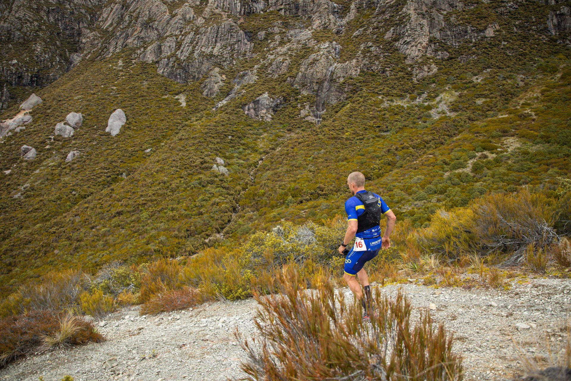 A man is running on a dirt trail in the mountains.