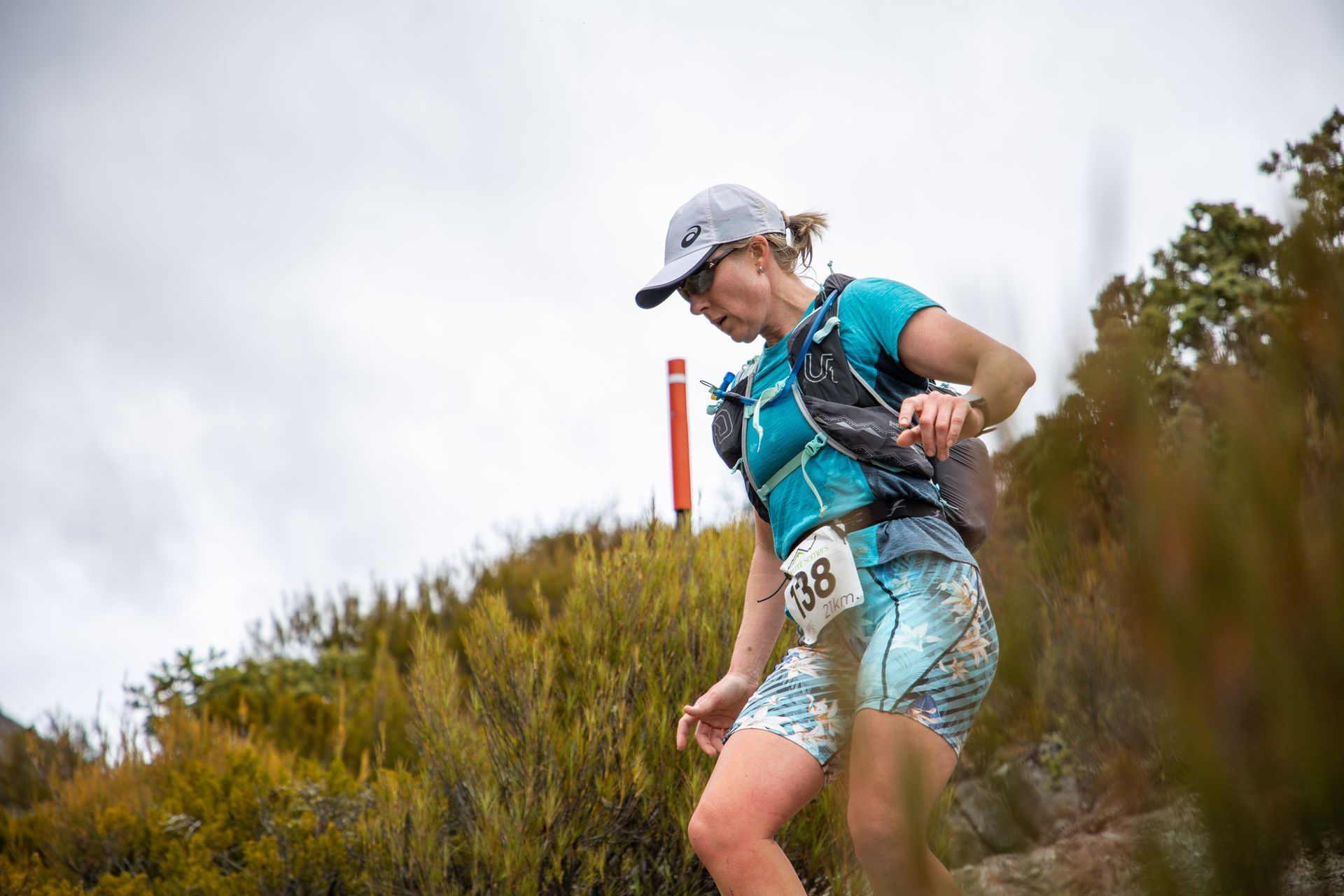 A woman is running on a trail in the woods.