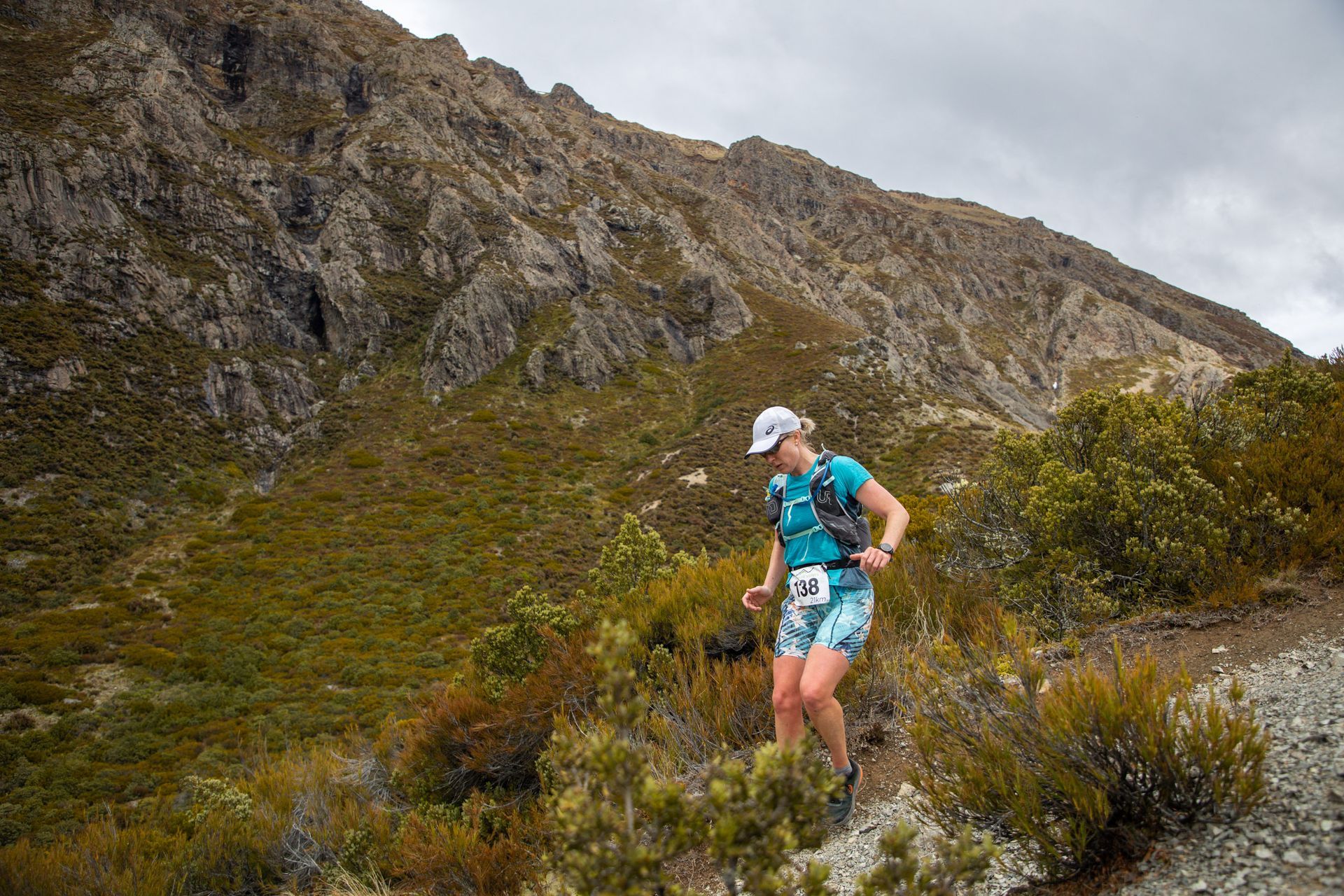 A woman is running on a trail in the mountains.
