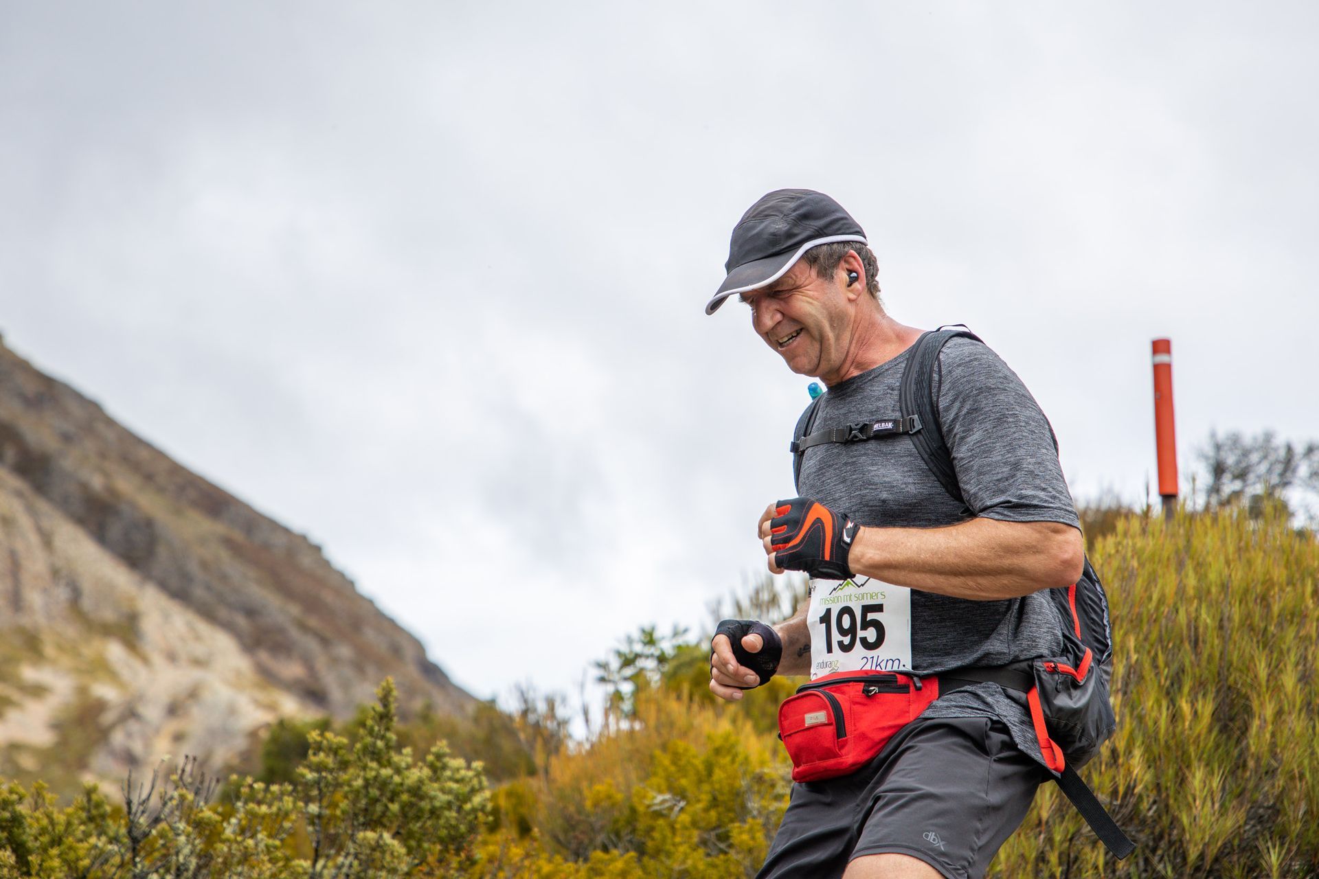 A man is running on a trail in the mountains.