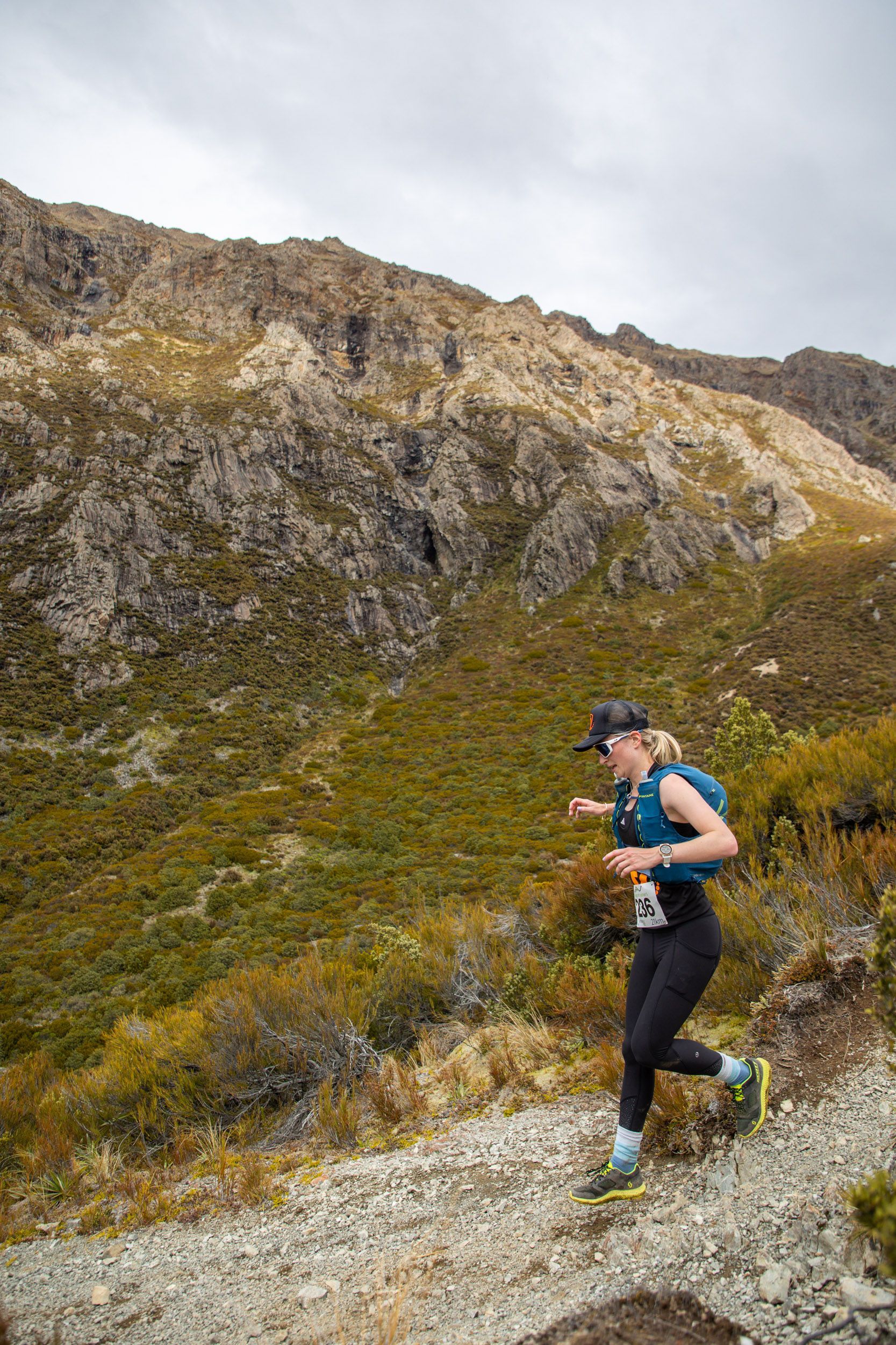 A woman is running on a trail in the mountains.