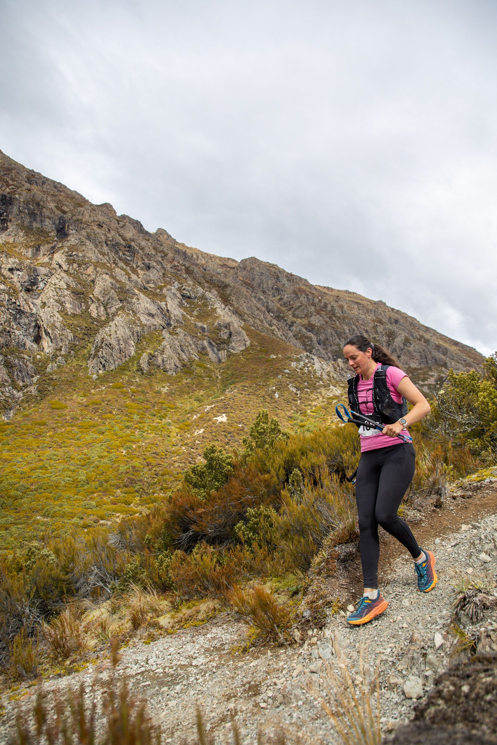A woman is running on a trail in the mountains.