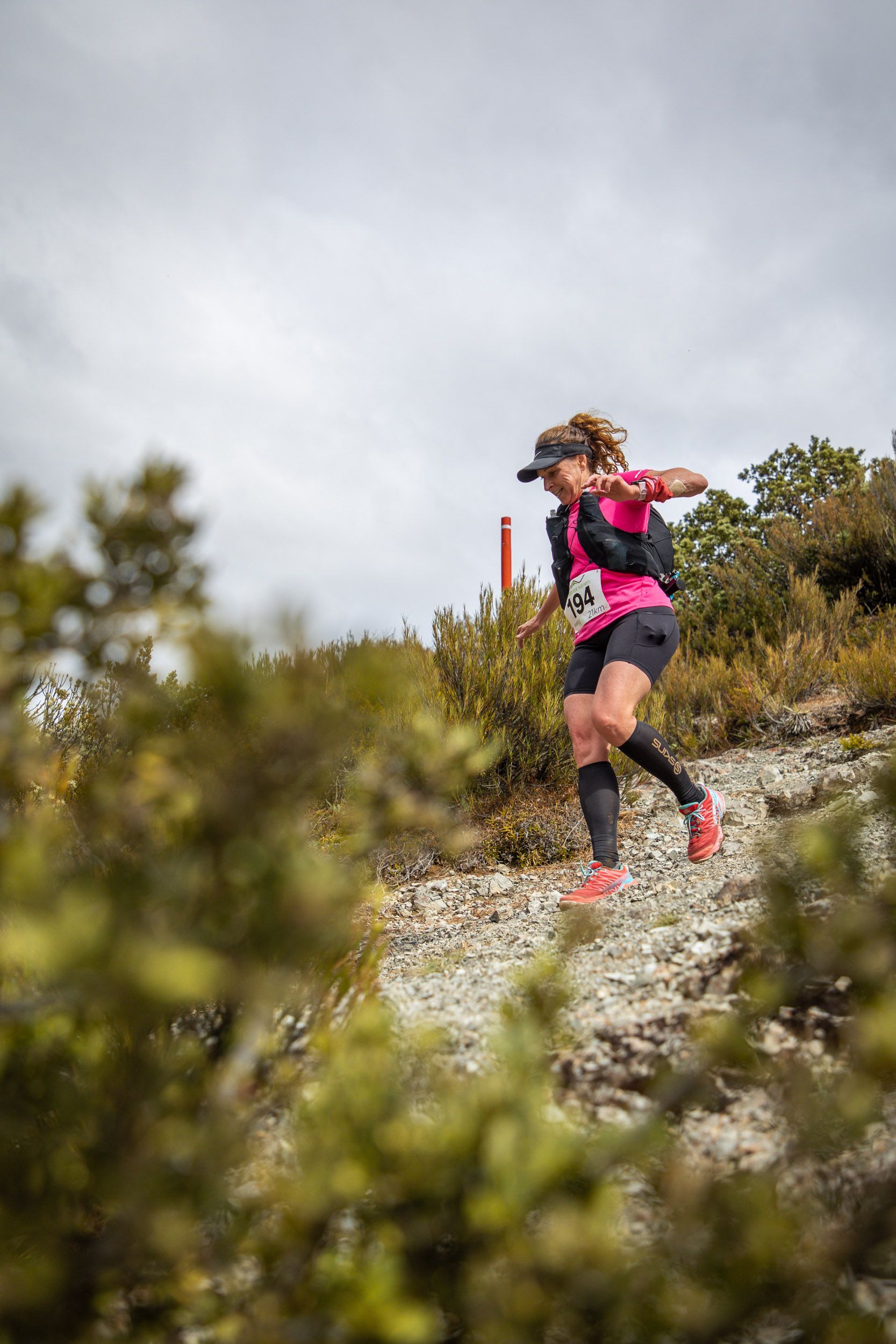 A woman is running on a trail in the woods.