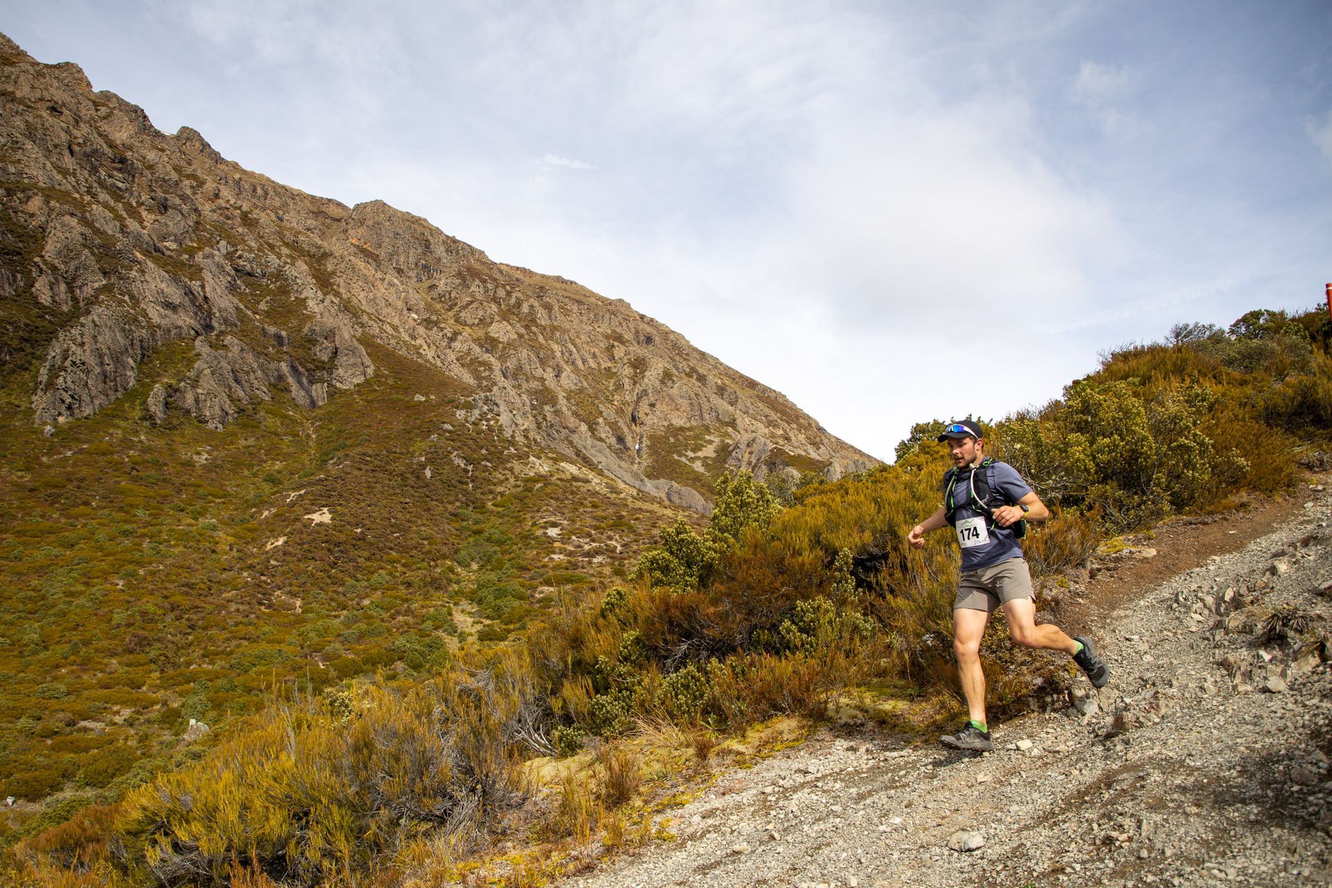 A man is running on a trail in the mountains.