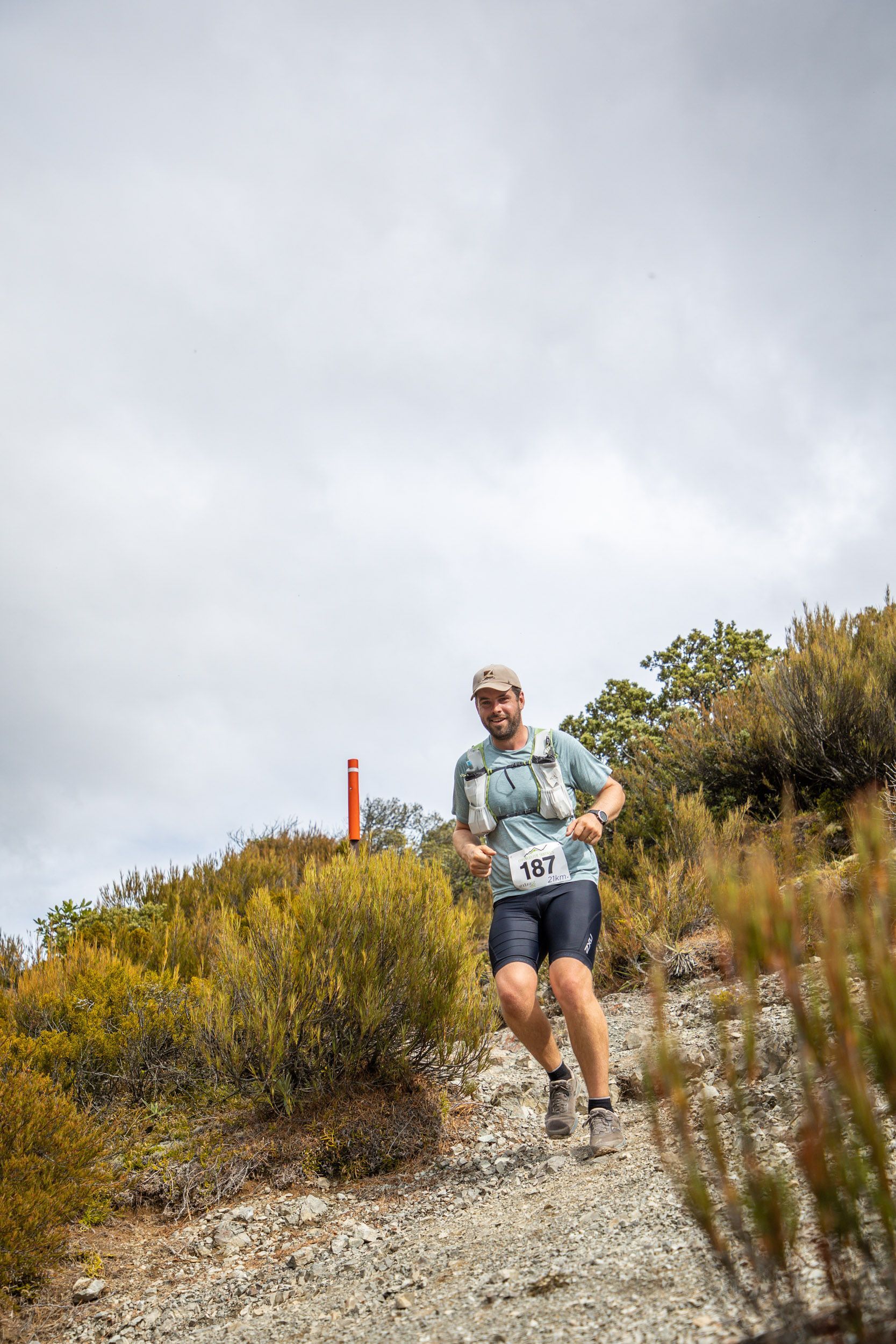 A man is running down a dirt path on a hill.