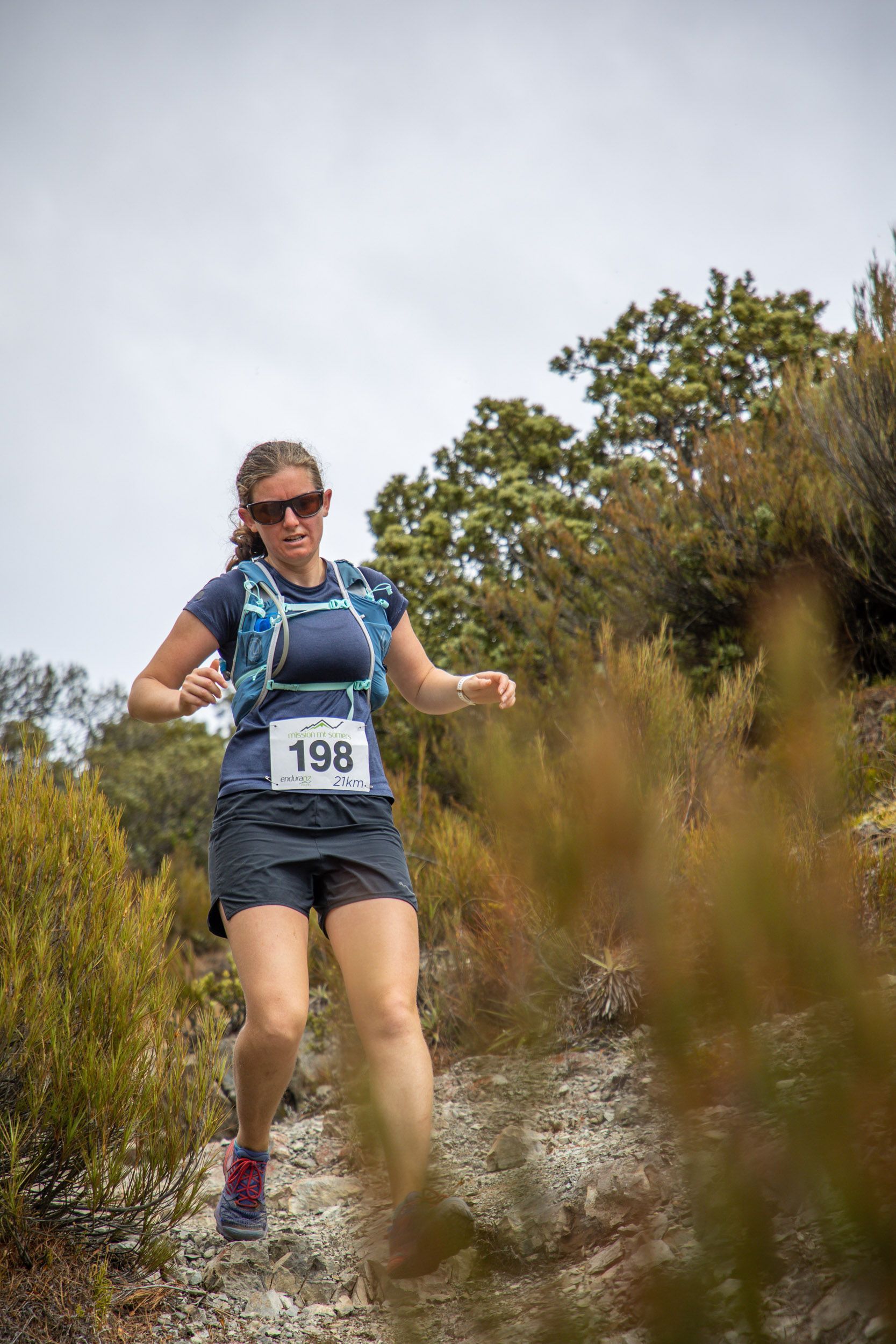 A woman is running on a trail in the woods.