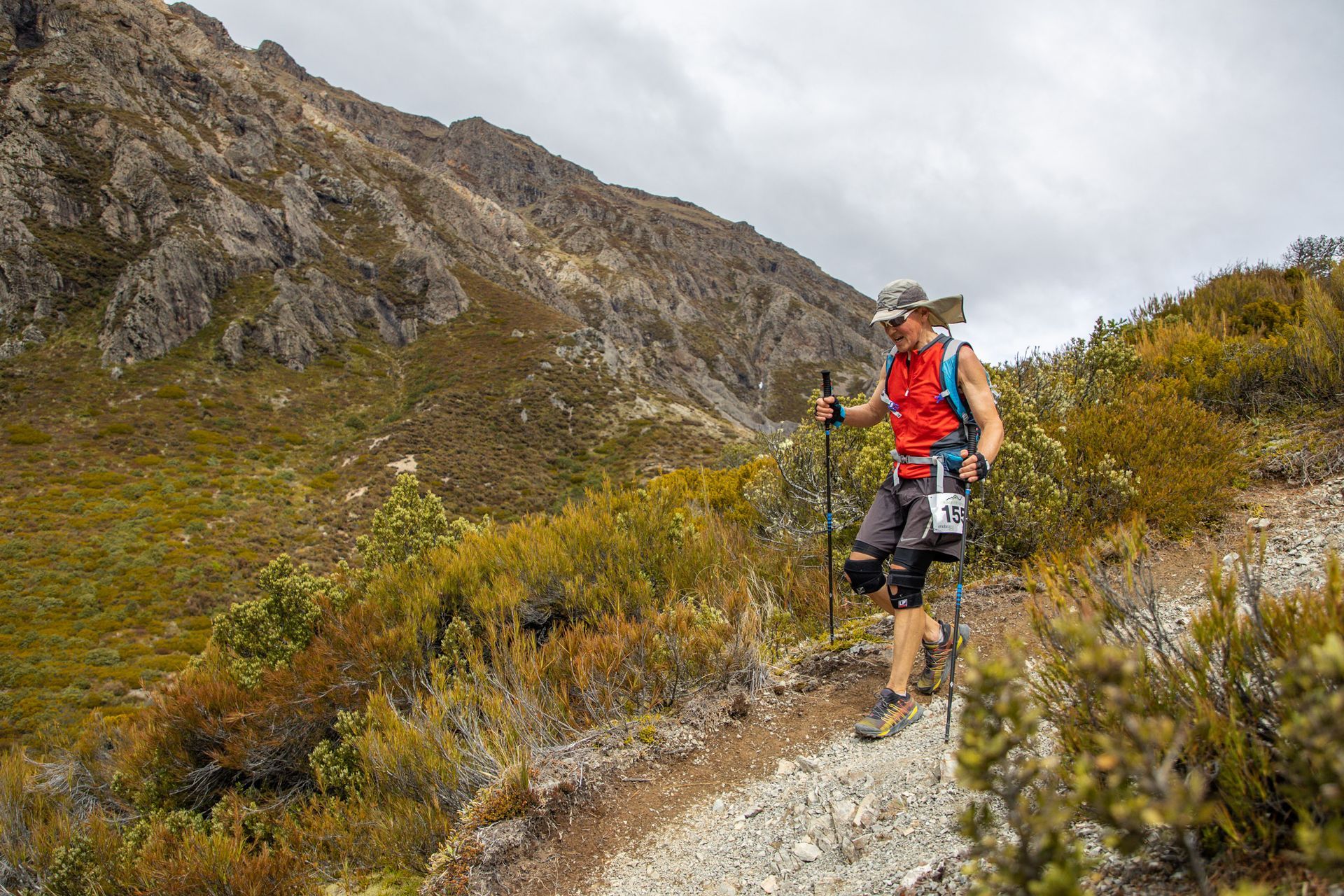 A man is hiking up a mountain with hiking poles.