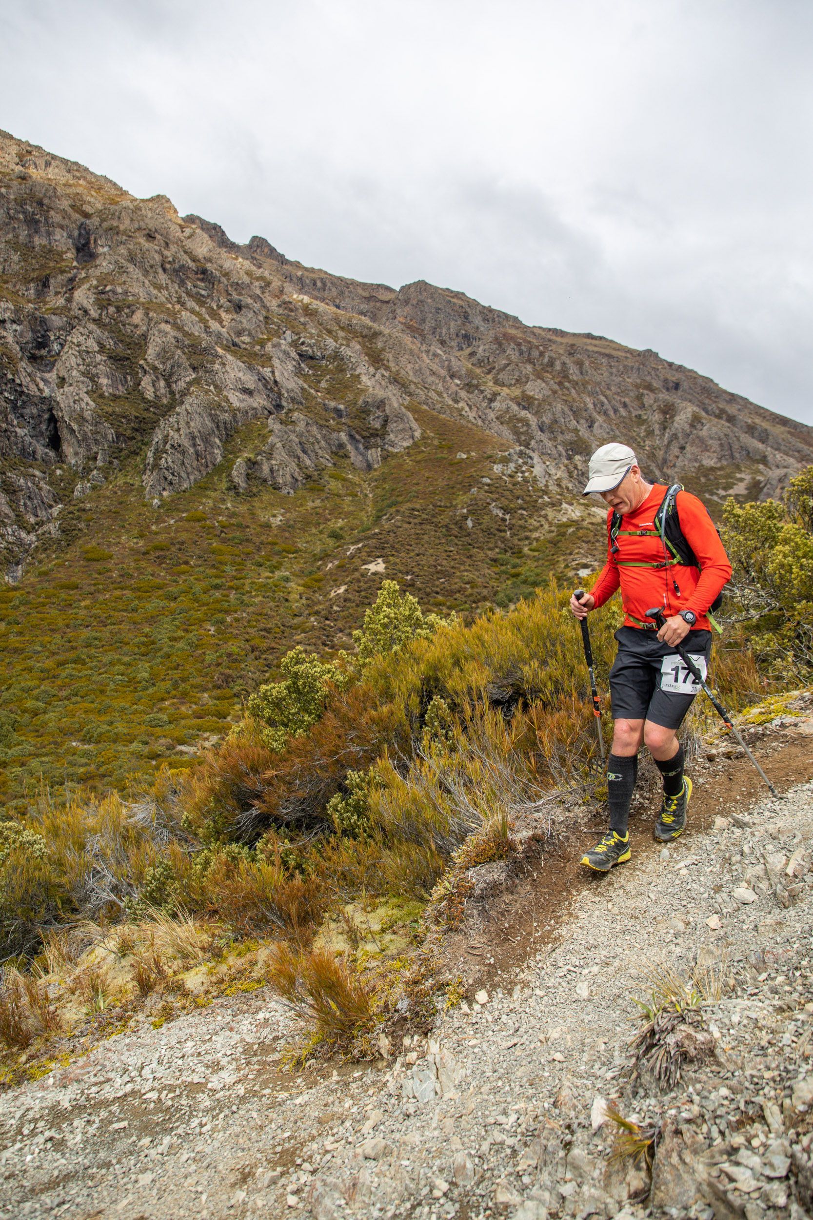 A man is walking on a trail in the mountains.