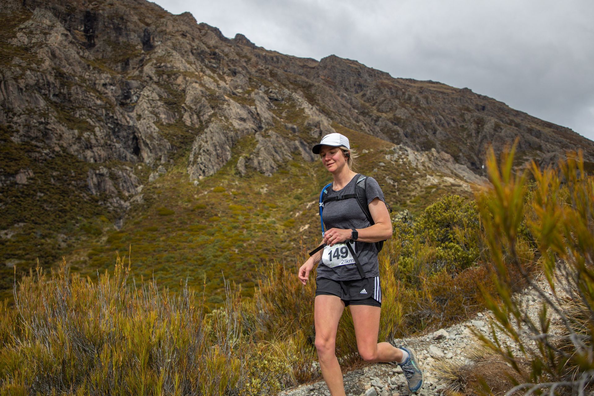 A woman is running on a trail in the mountains.