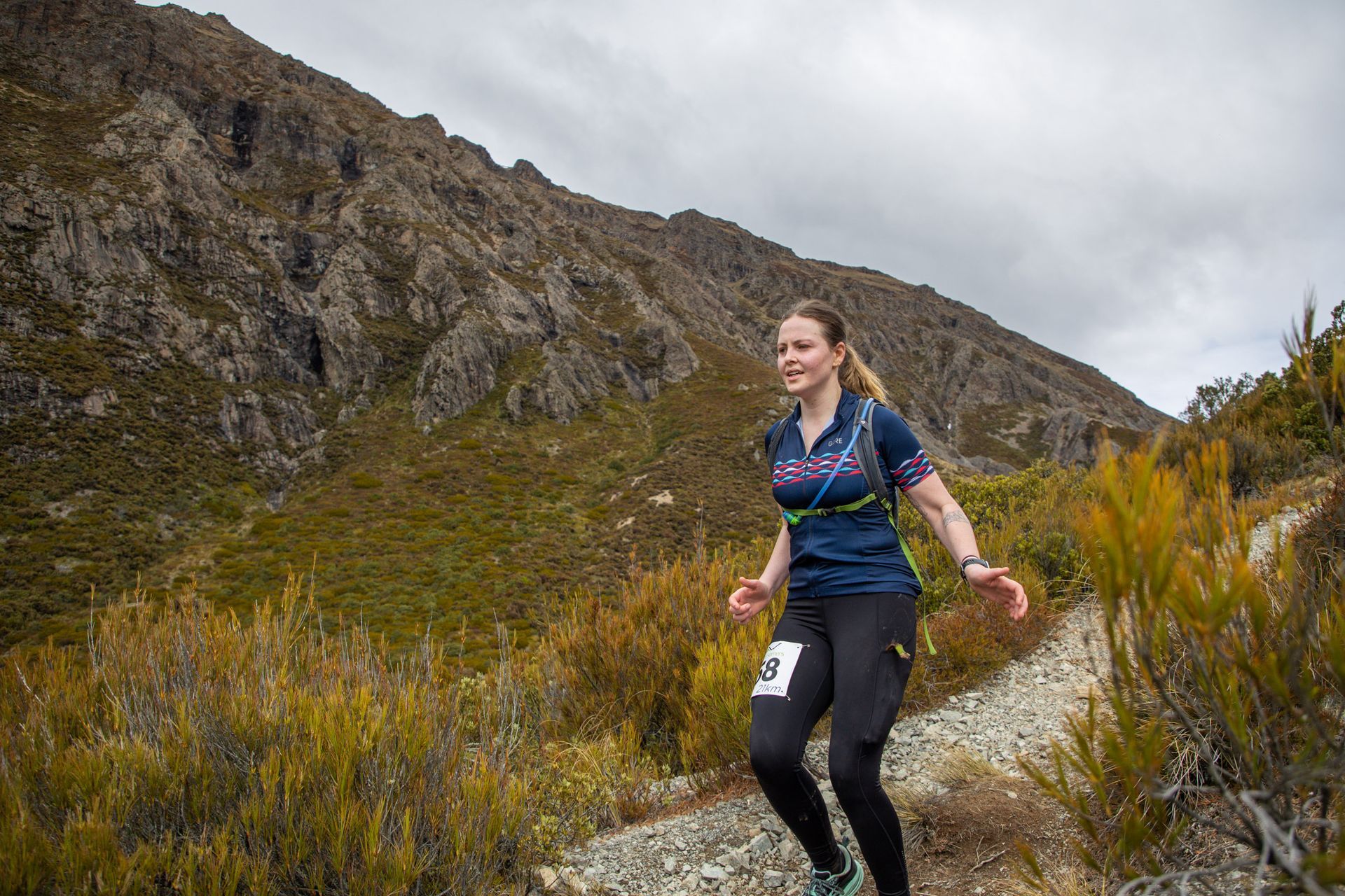 A woman is running on a trail in the mountains.