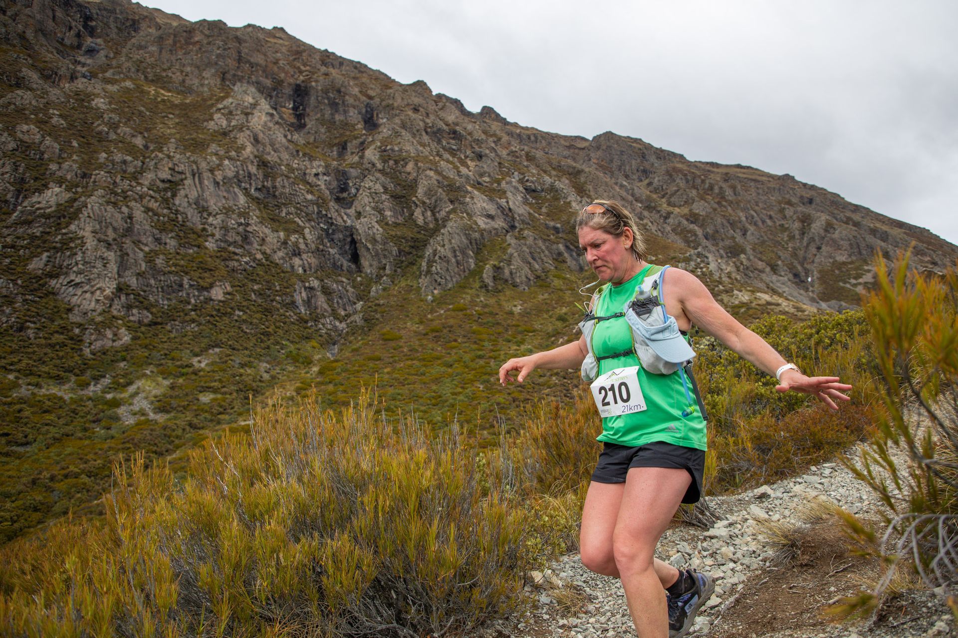A woman is running on a trail in the mountains.