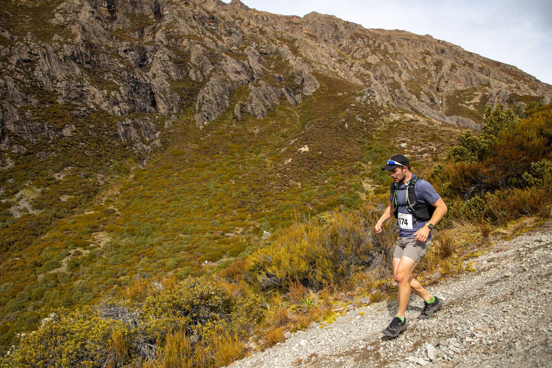 A man is running on a trail in the mountains.