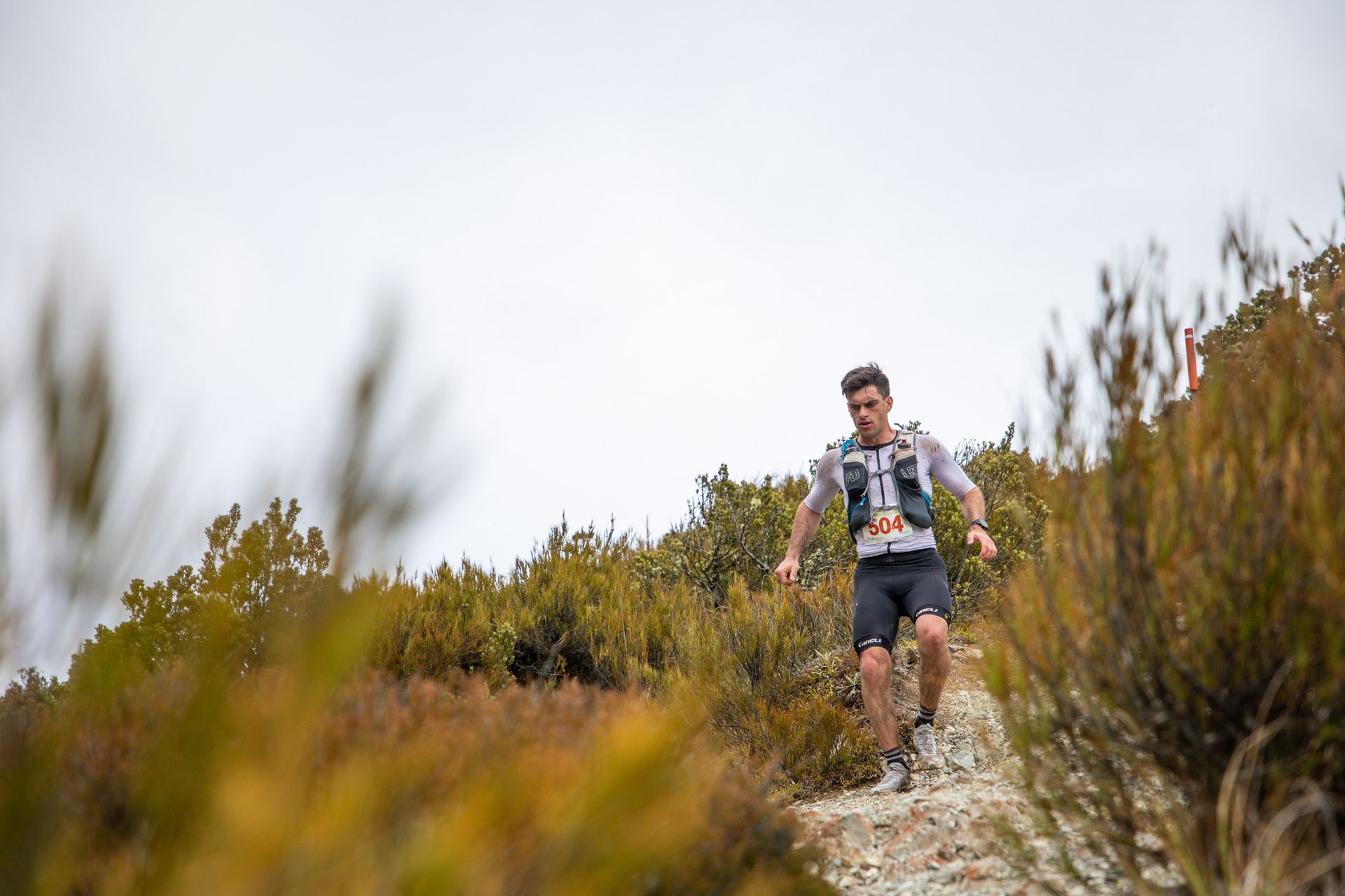 A man is running on a trail in the woods.
