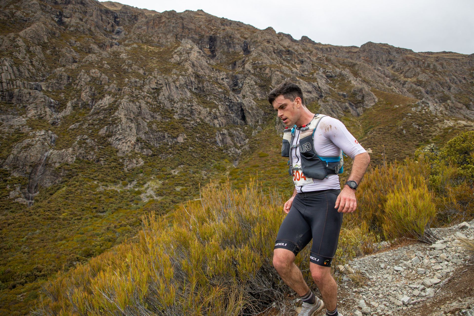 A man is running on a trail in the mountains.