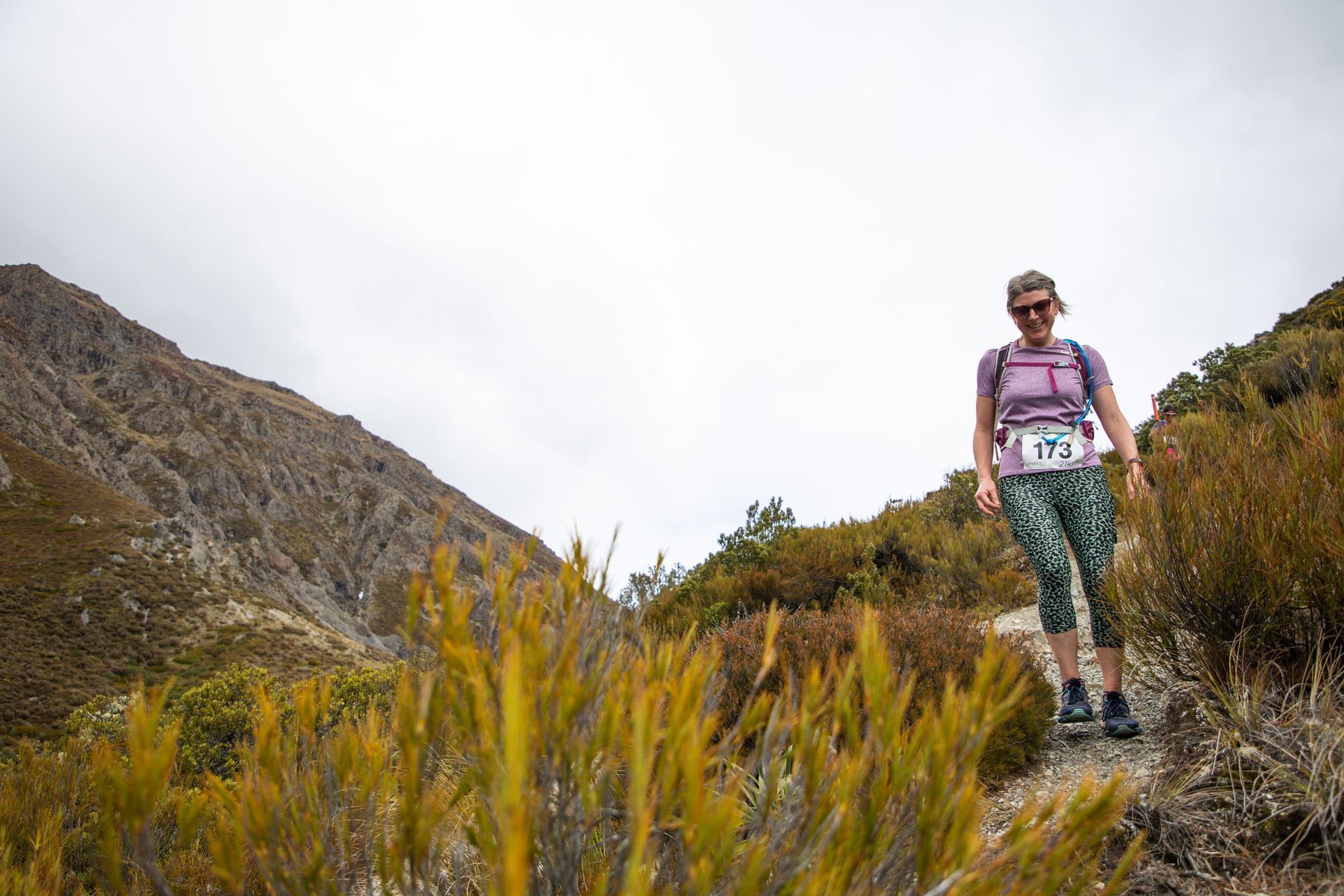 A woman is walking on a trail in the mountains.