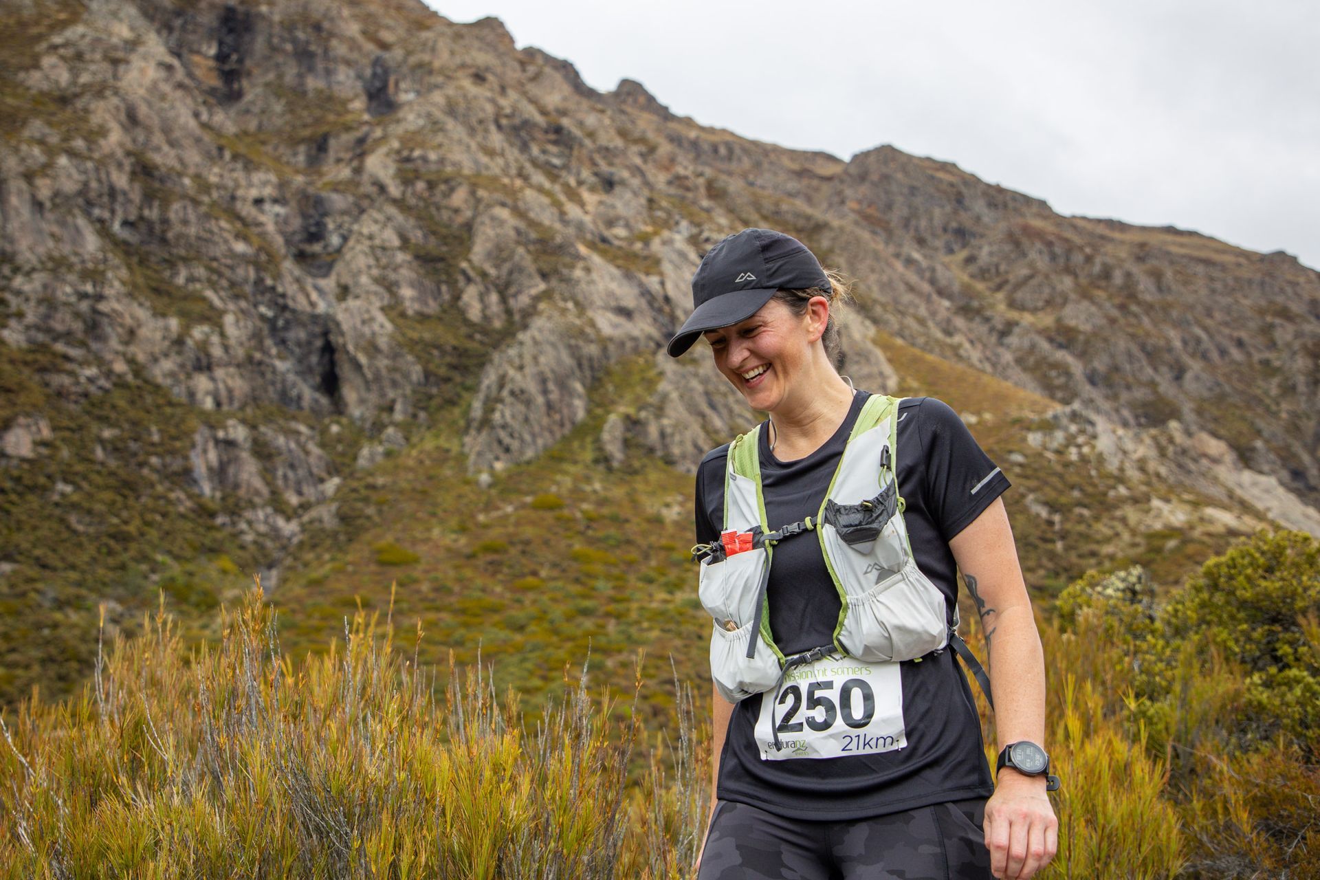 A woman is standing in front of a mountain wearing a number 250 bib.