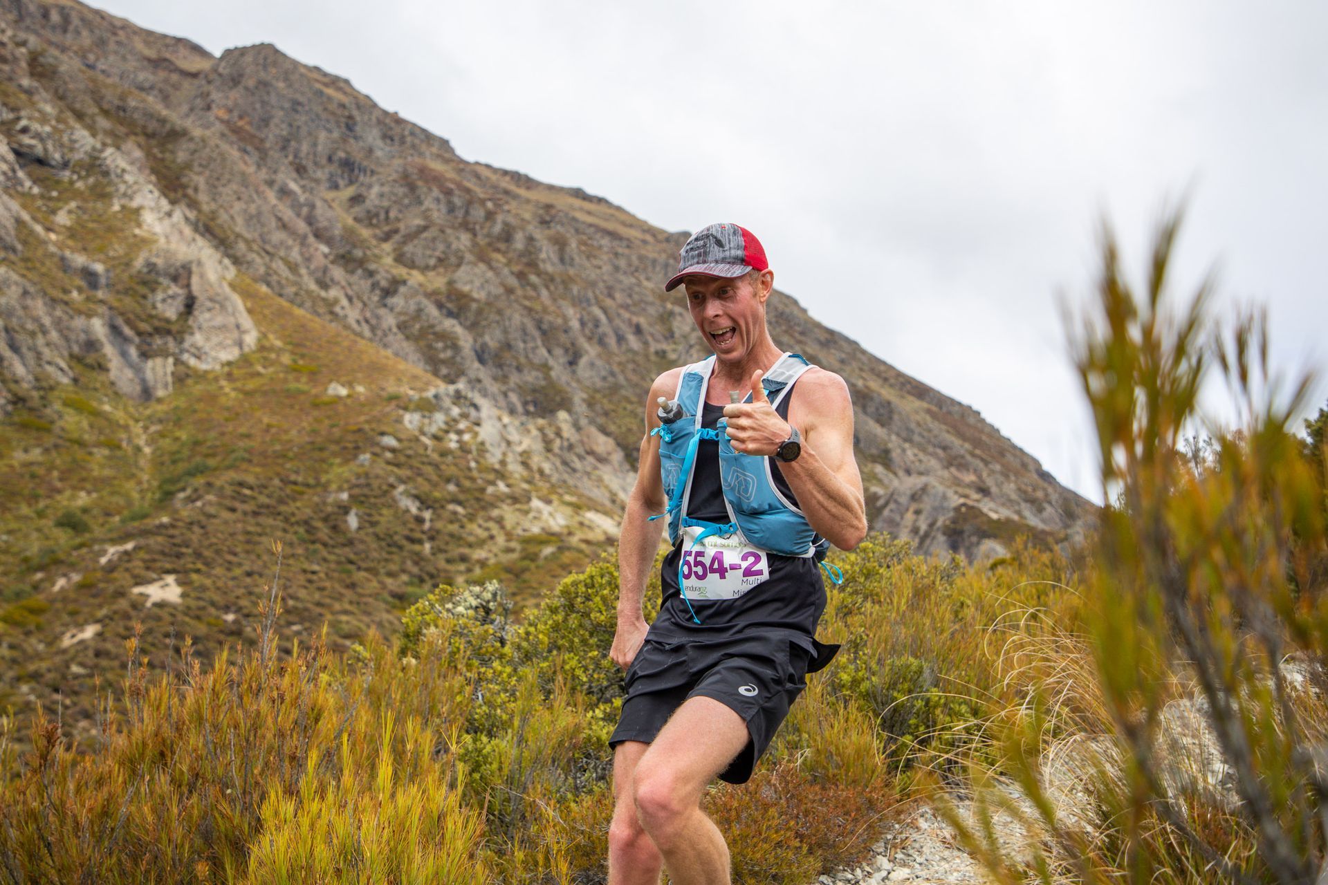 A man is running on a trail in the mountains.