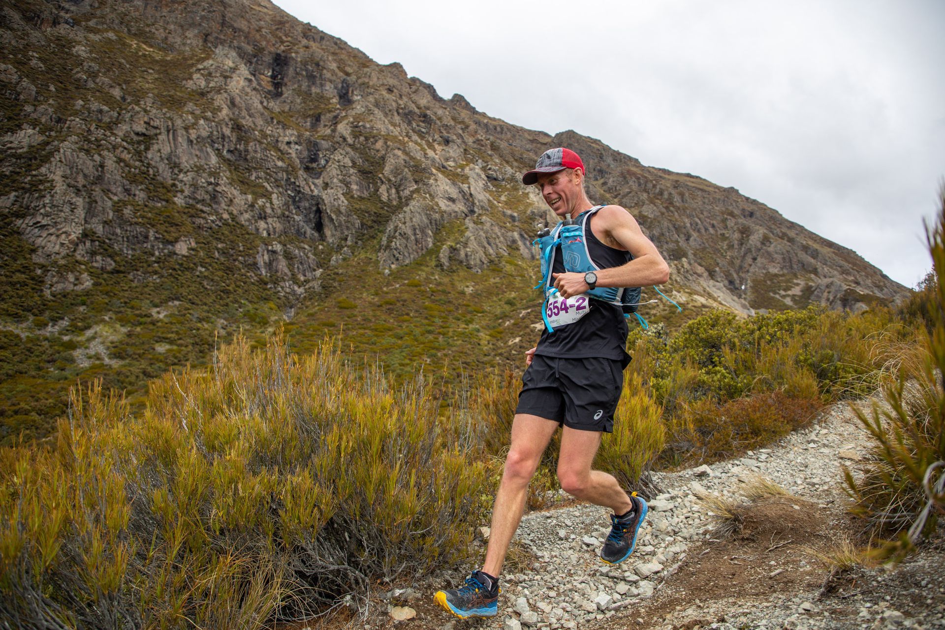 A man is running on a trail in the mountains.