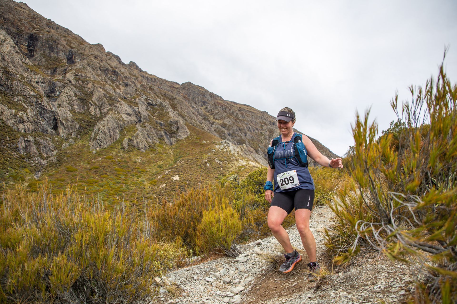 A woman is running on a trail in the mountains.