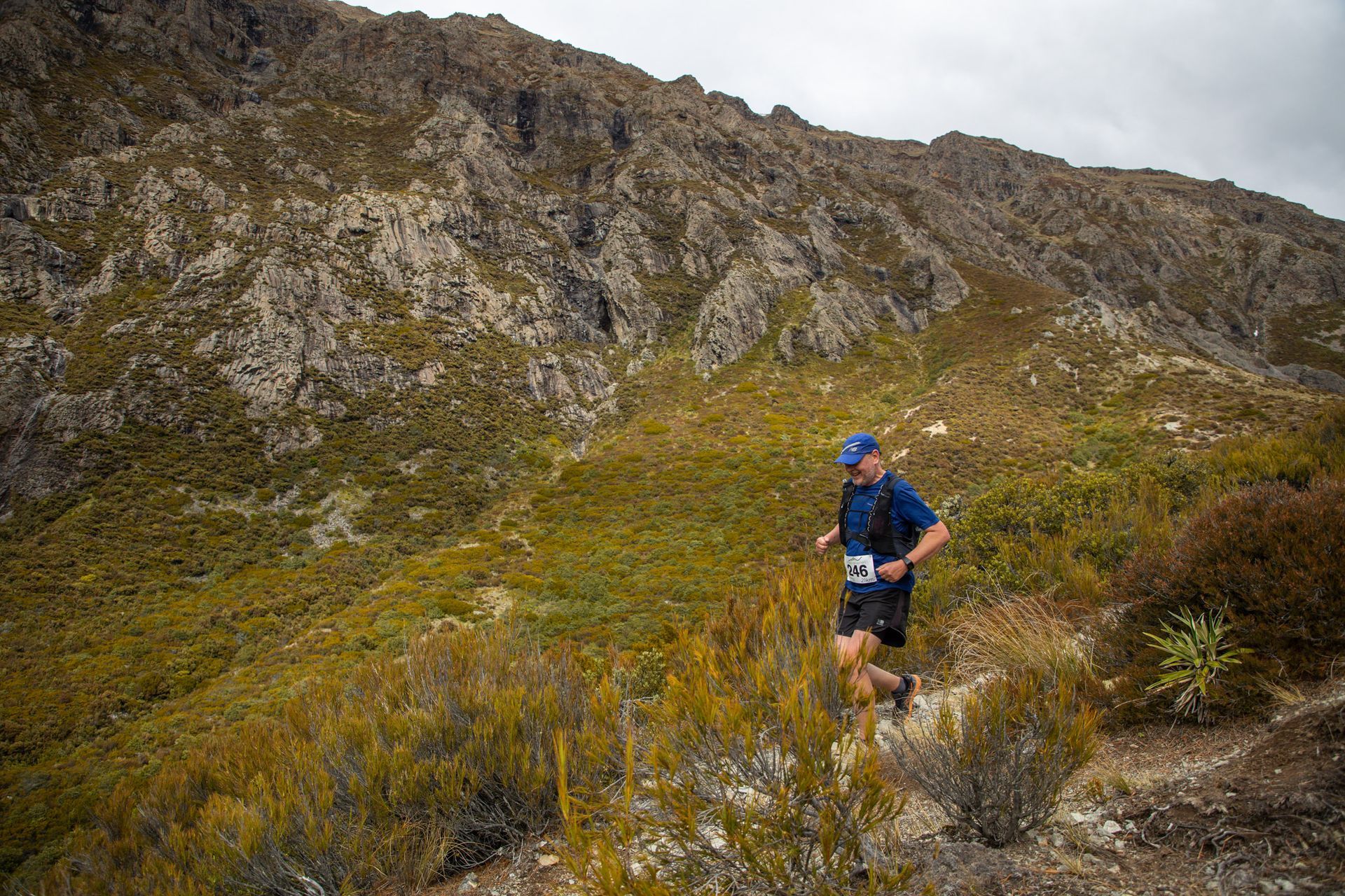 A man is running on a trail in the mountains.