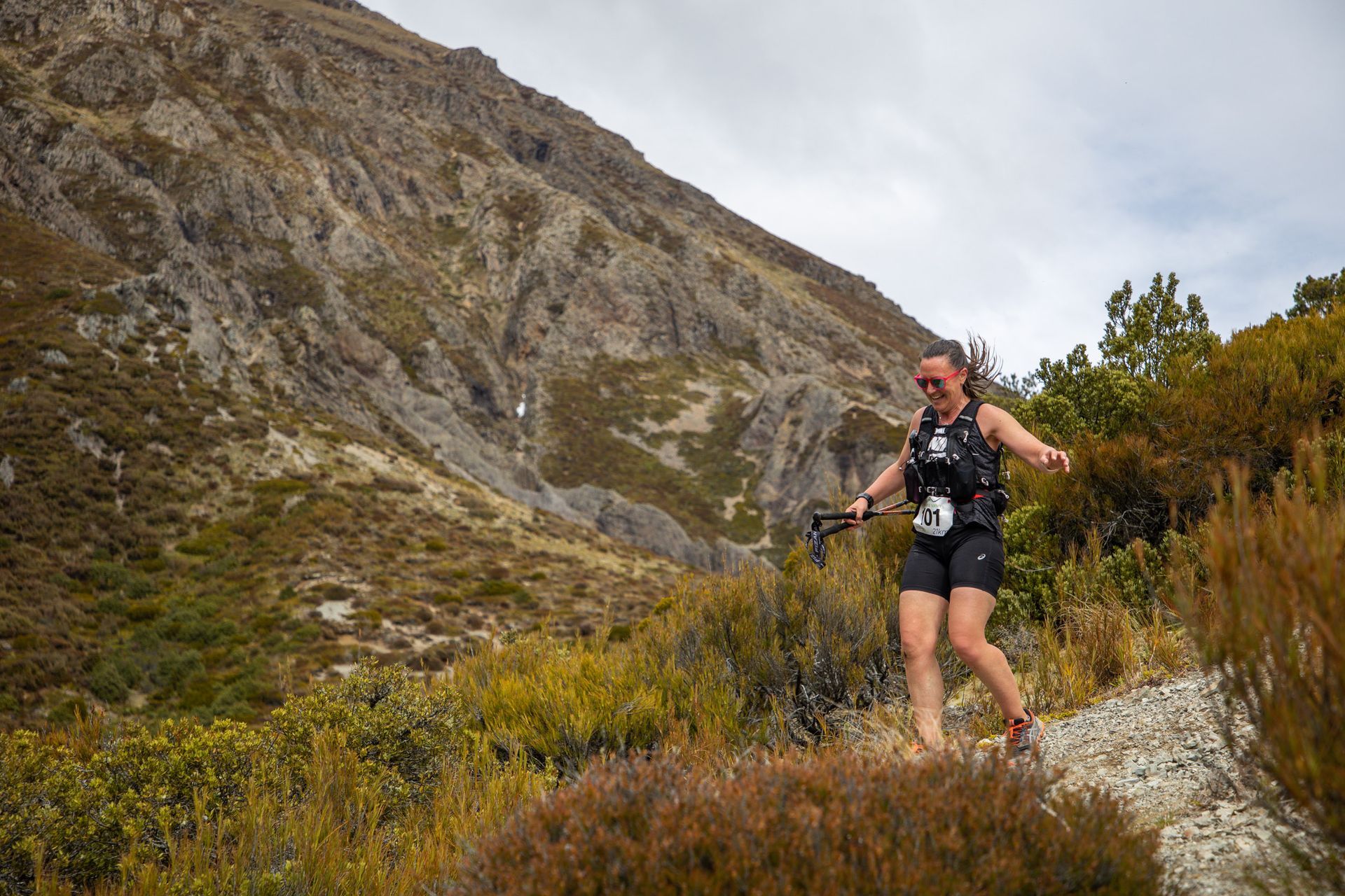 A woman is running on a trail in the mountains.